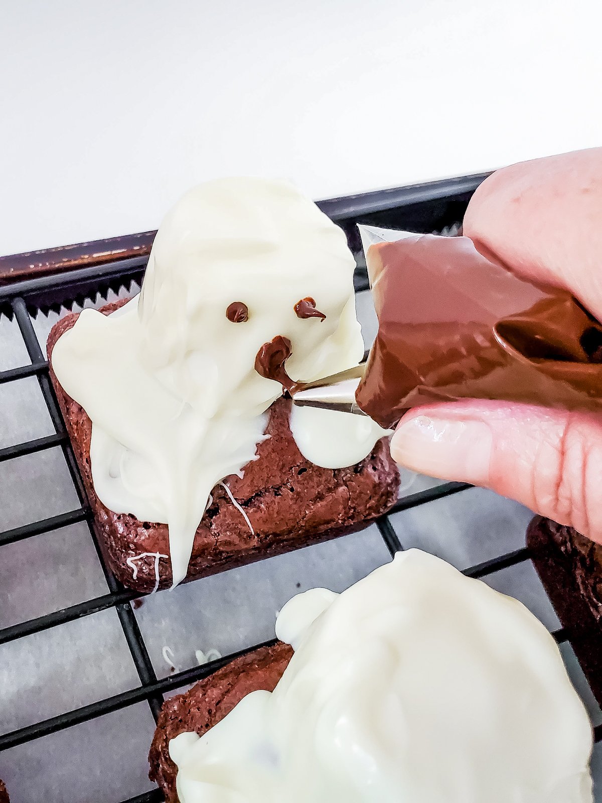 piping bag drawing face on ghost brownies