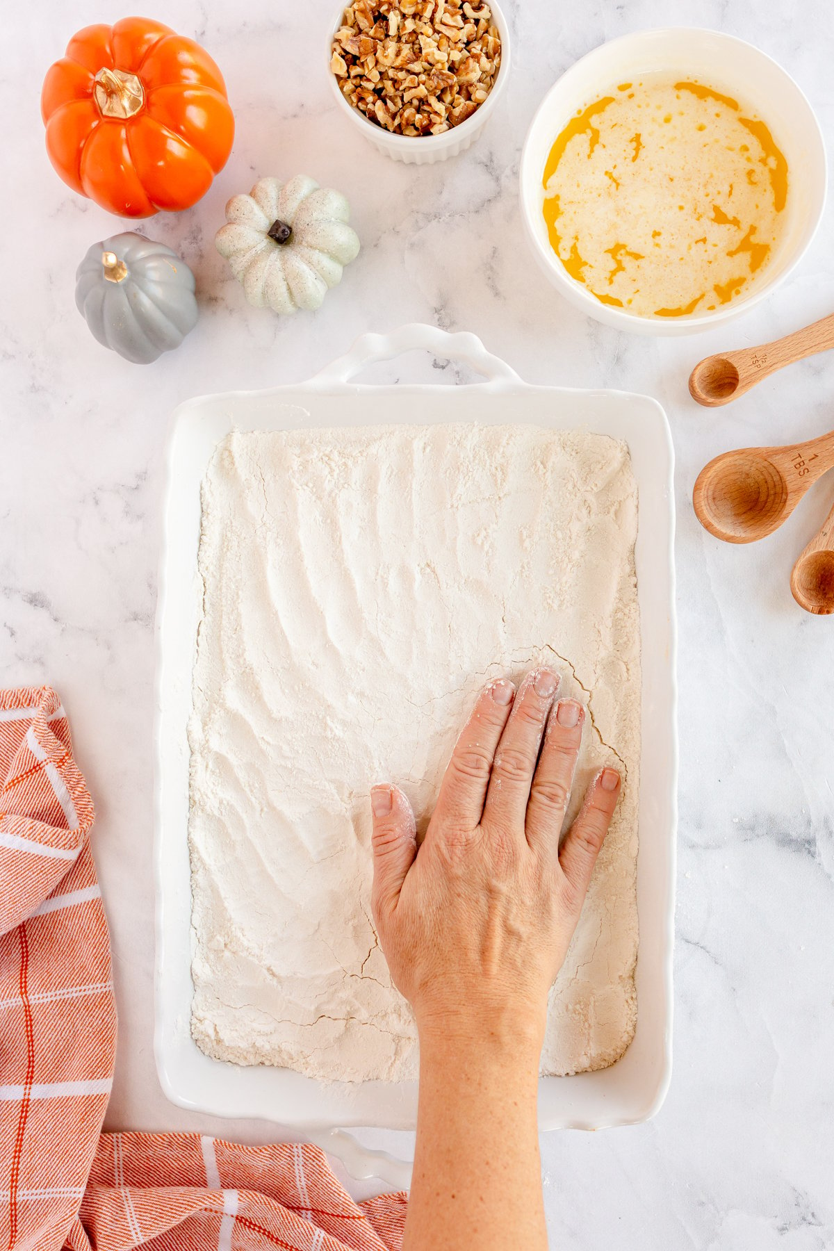 Hand patting down cake mix in a baking dish