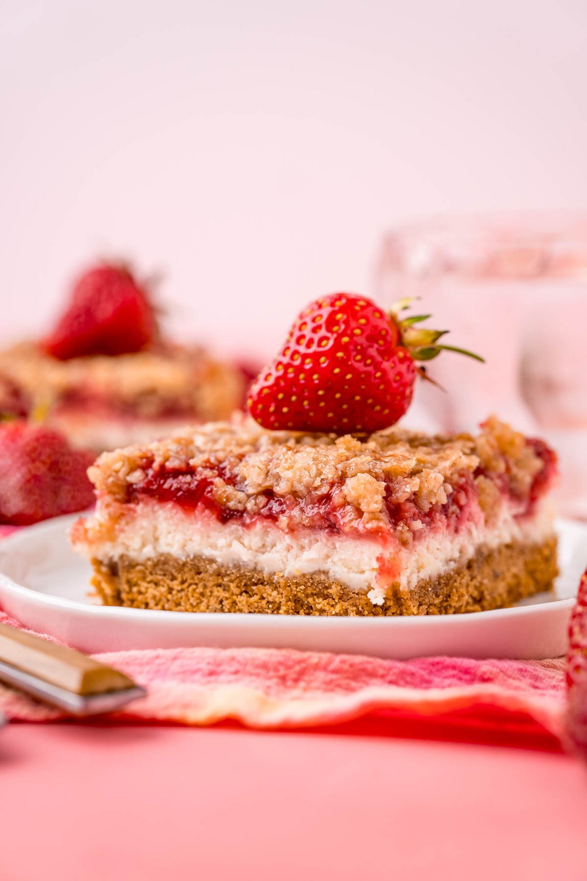 a white plate and two strawberry cheesecake bars