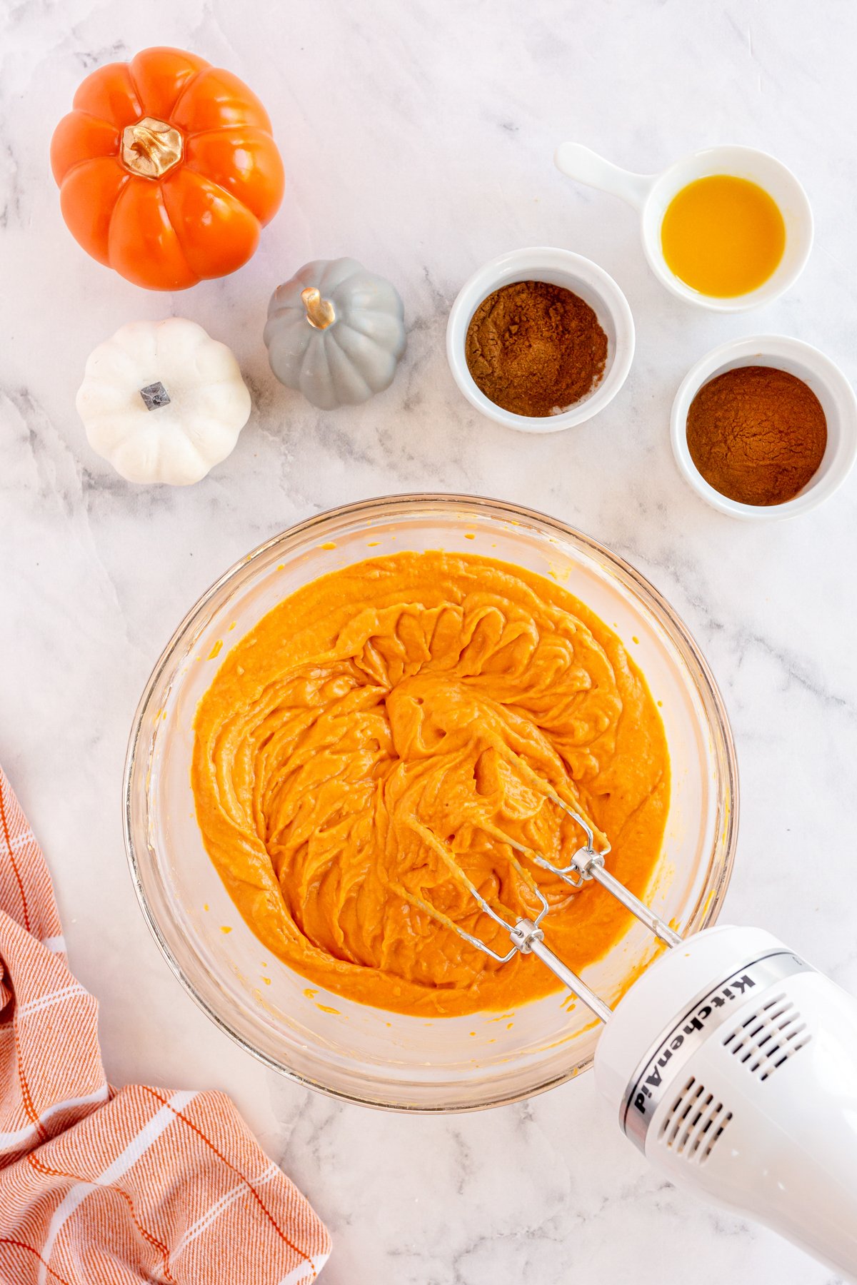 hand mixer mixing pumpkin dip in a glass bowl