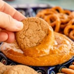 hand dipping a gingersnap in a pumpkin pie dip