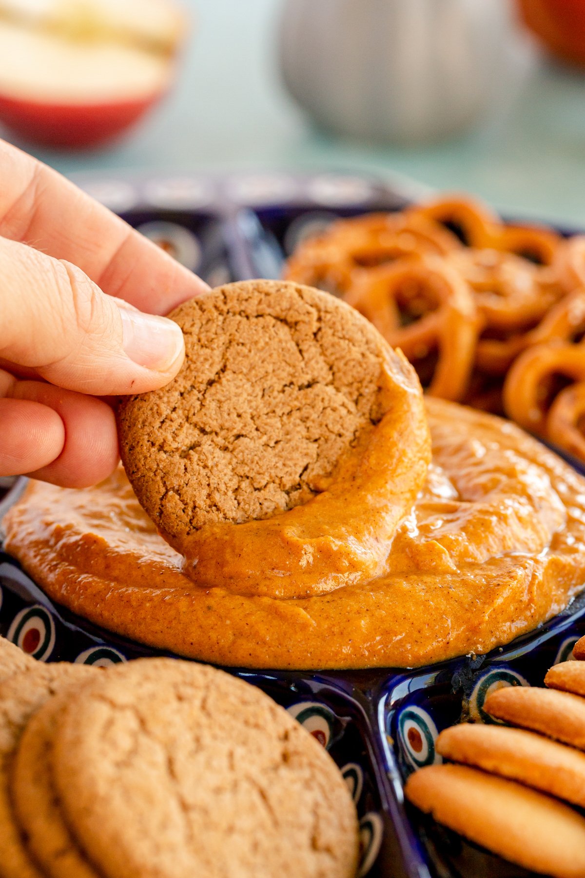 hand dipping a gingersnap in a pumpkin pie dip