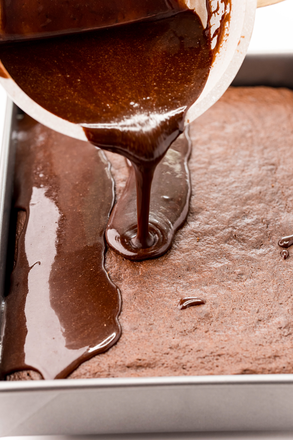 pouring chocolate frosting on a dr pepper cake