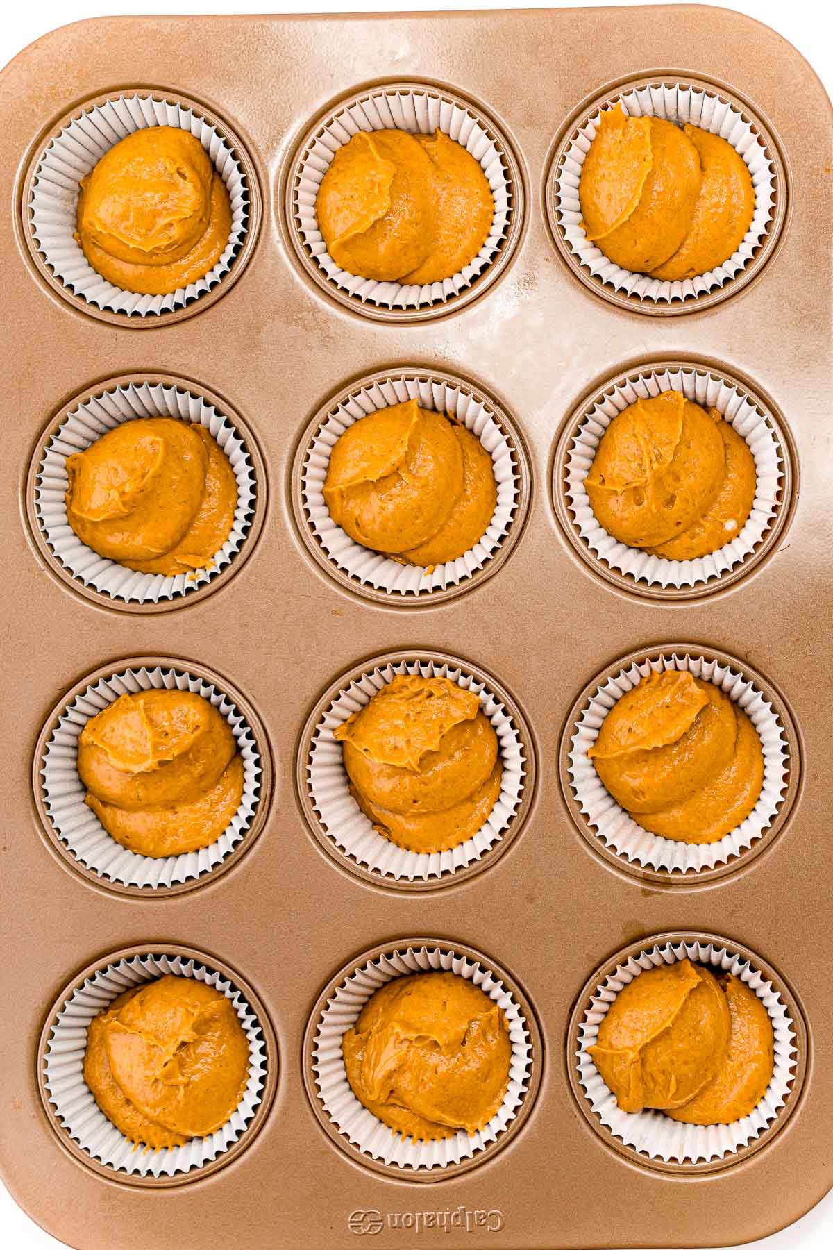 muffin tin with unbaked pumpkin cupcakes