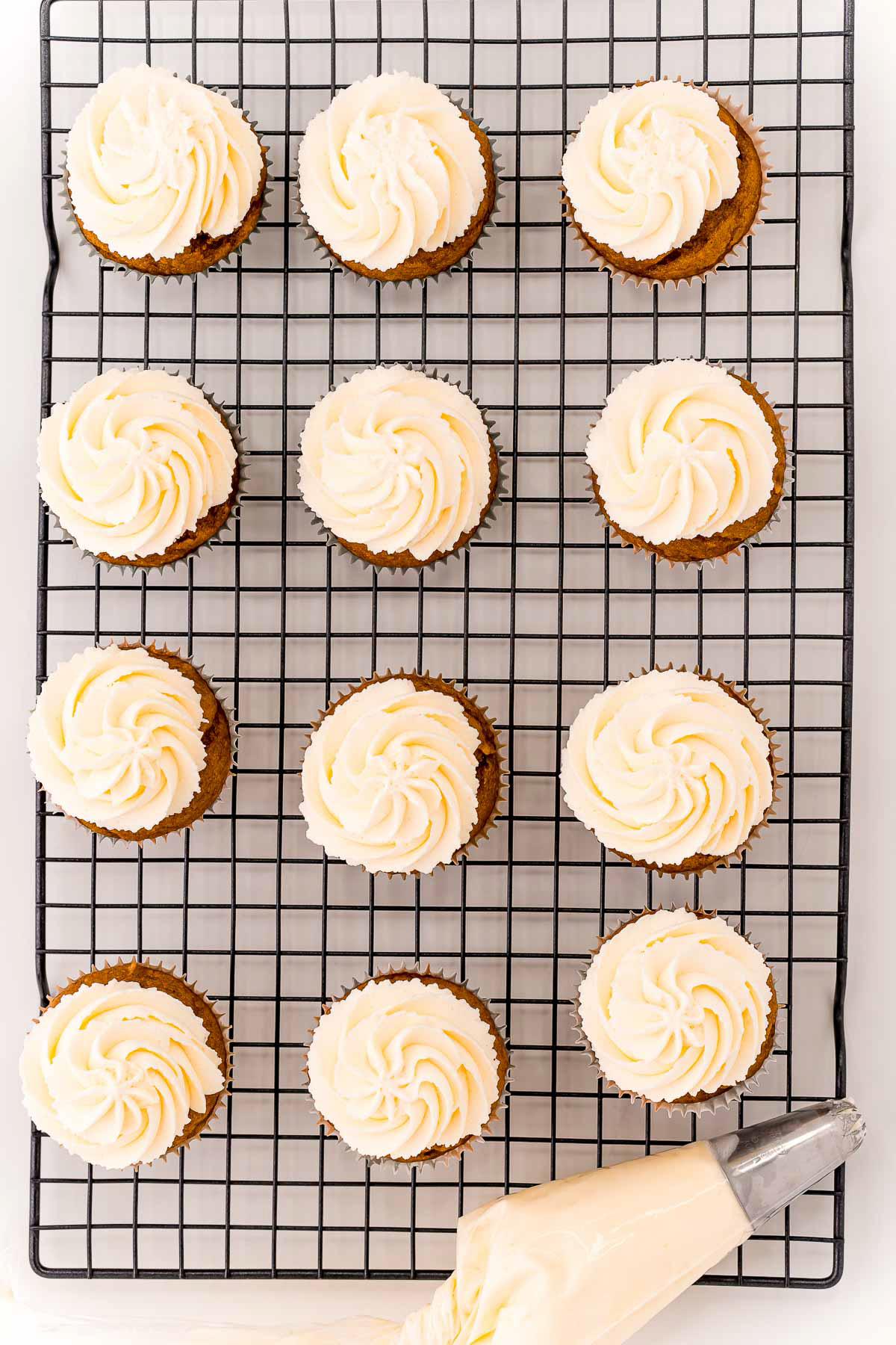 frosted pumpkin cupcakes on a cooling rack
