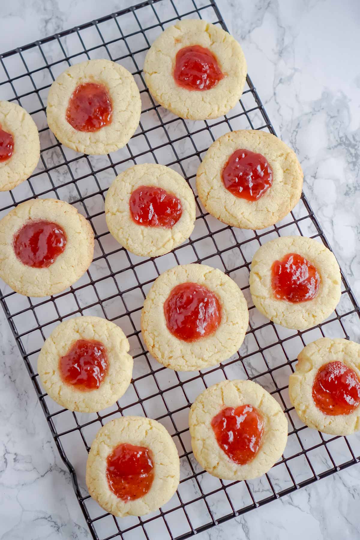 strawberry thumbprint cookies on a wire cooling rack