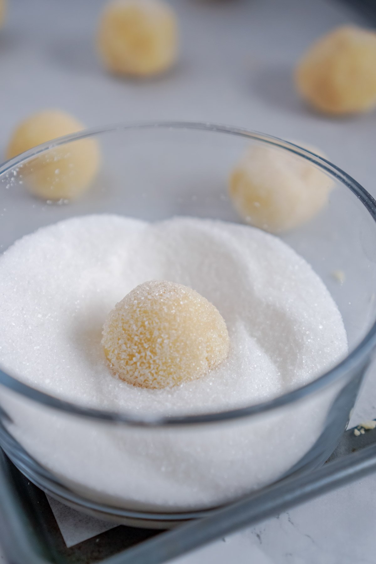 thumbprint cookie dough in a bowl of sugar