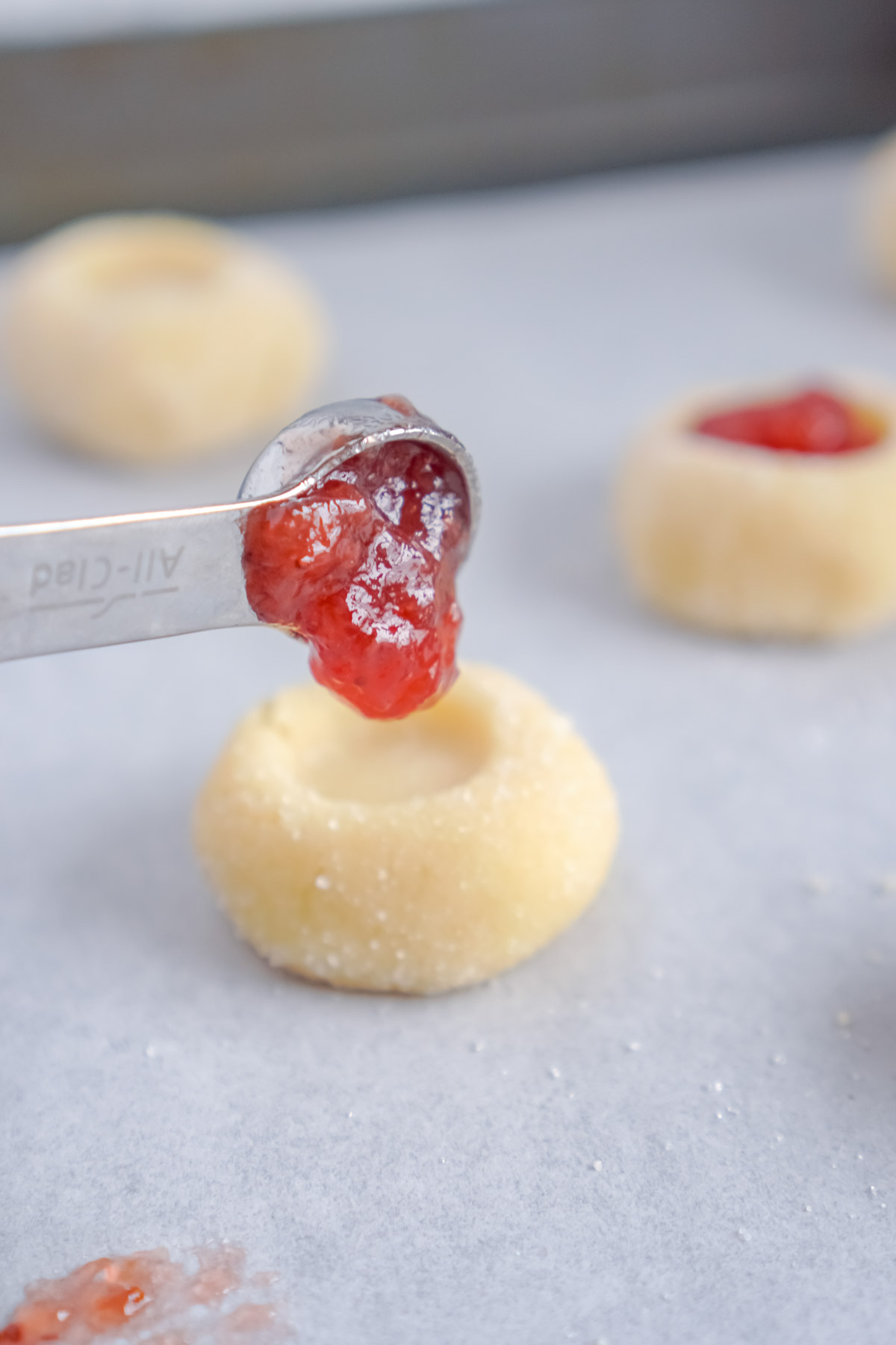 adding jam to the top of a thumbprint cookie