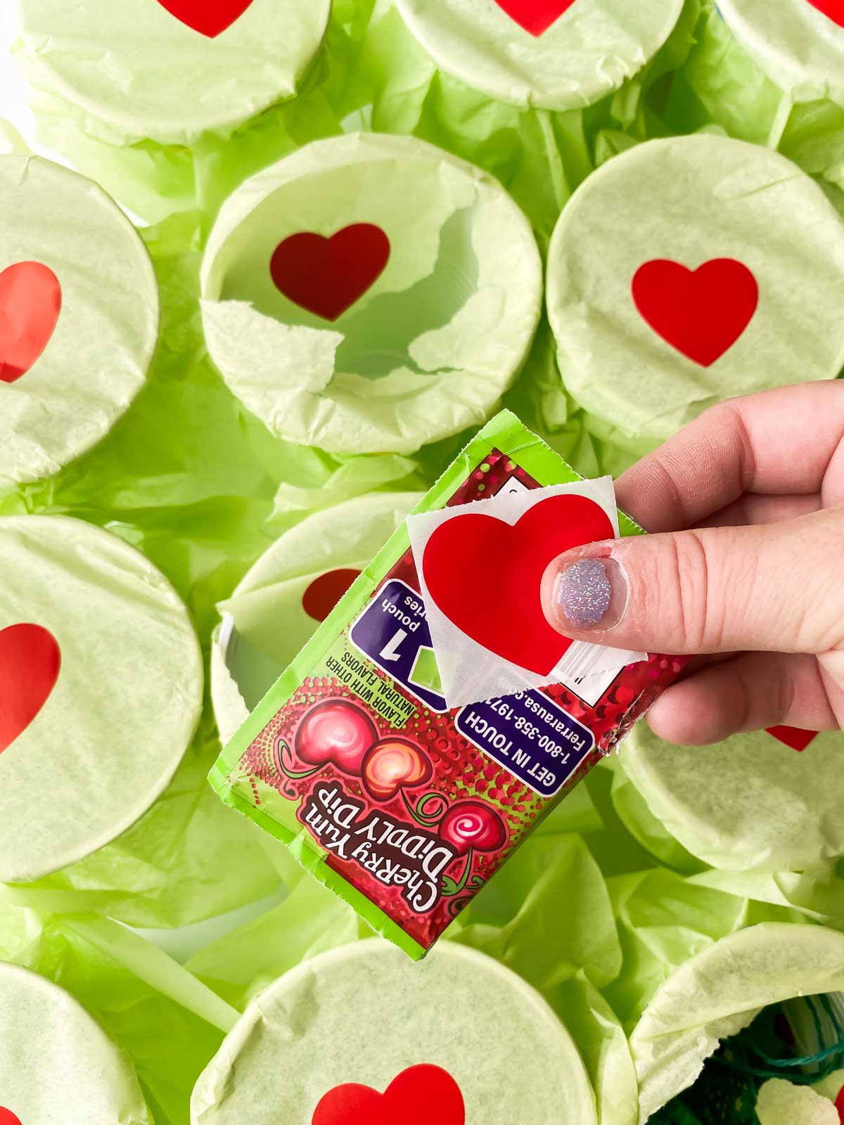 hand holding a Fun Dip and a heart sticker