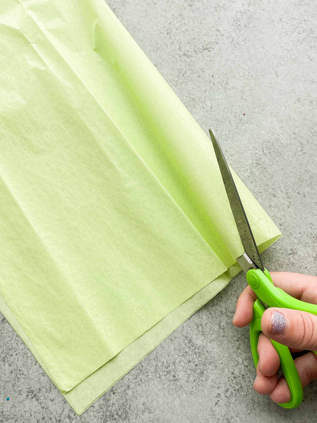 scissors cutting green tissue paper