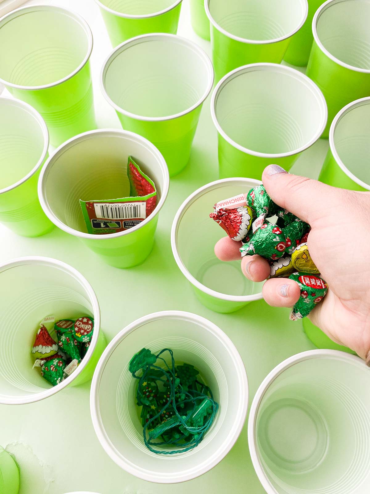 hand holding Grinch kisses above green cups