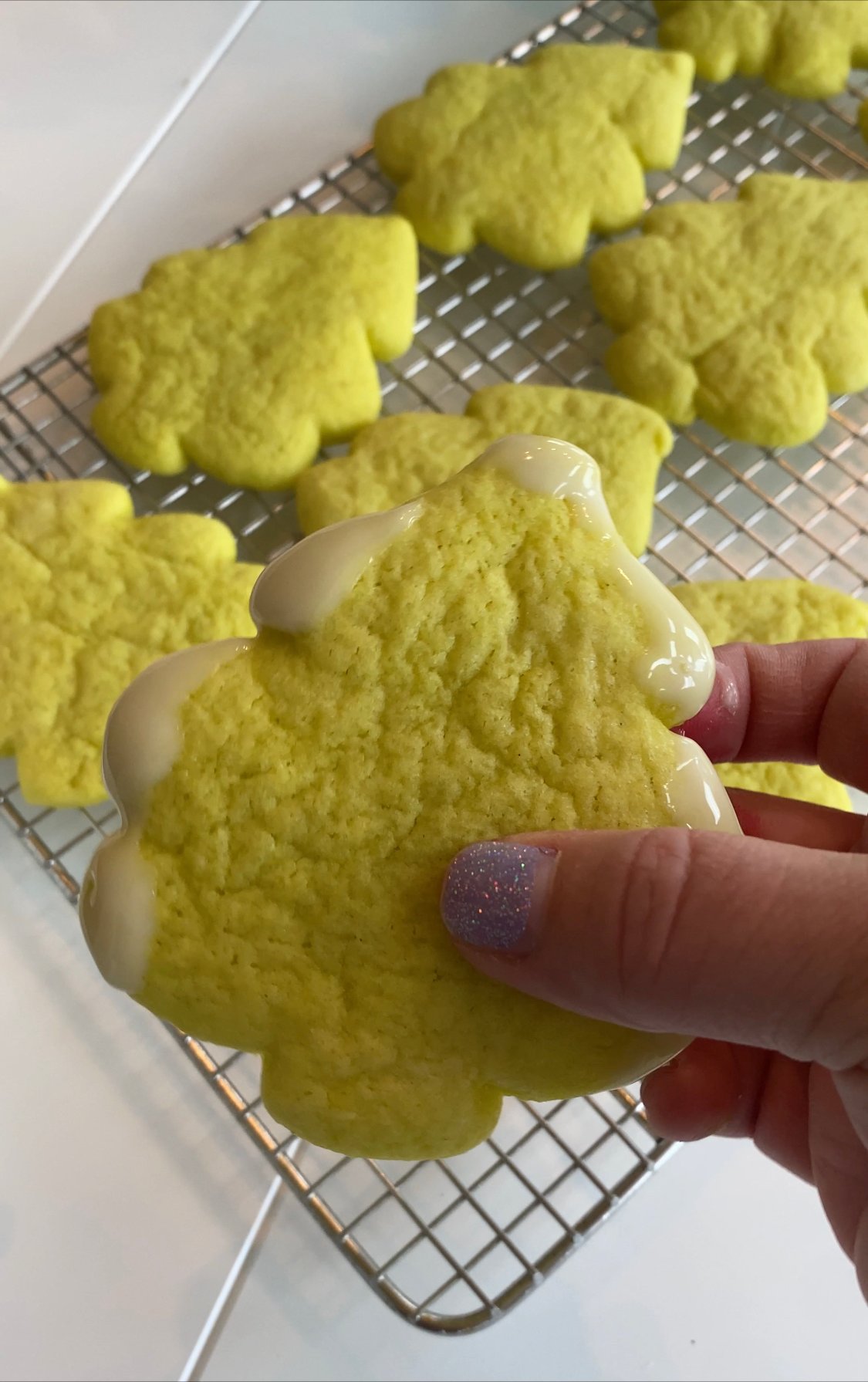 hand holding a Grinch sugar cookie with glazed tips