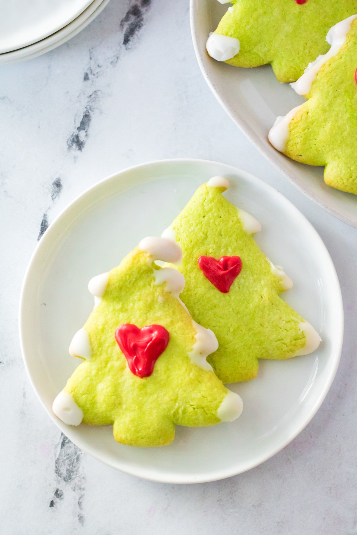 two Grinch sugar cookies on a white plate