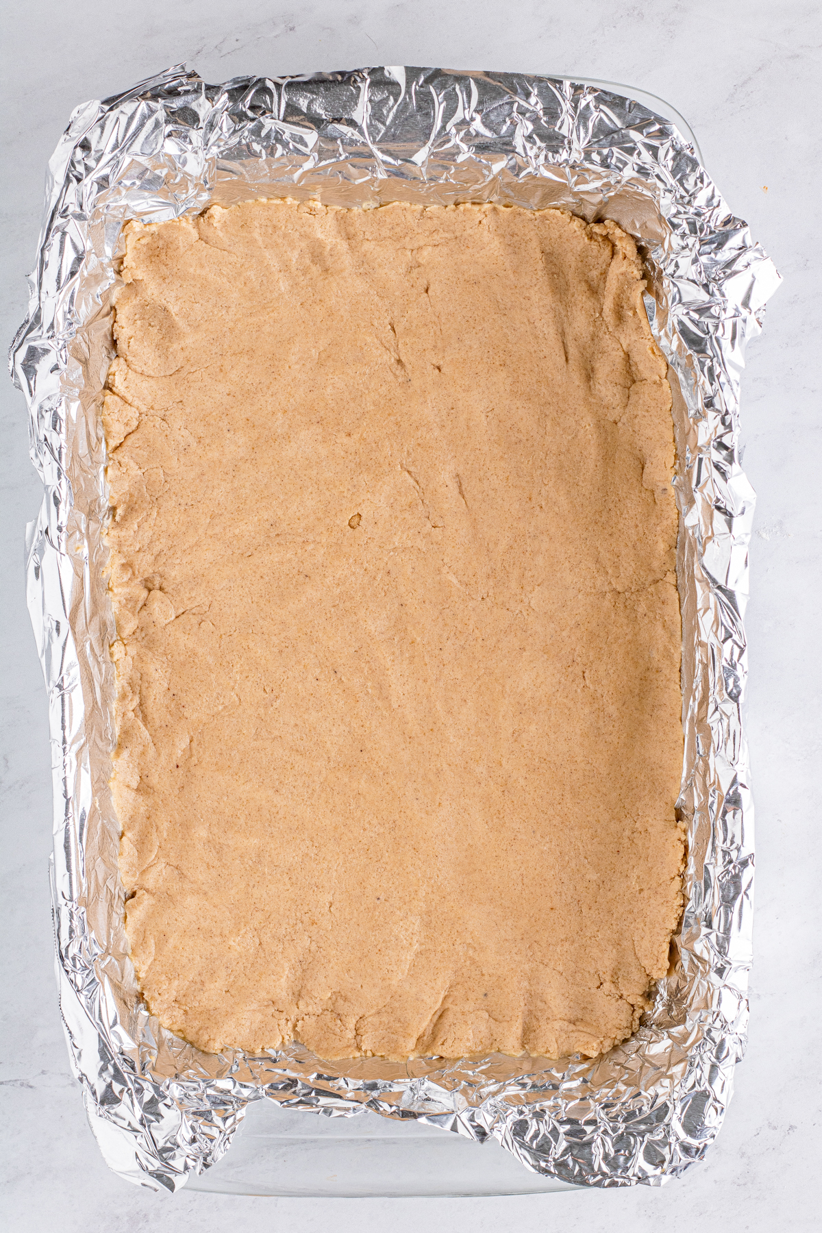 unbaked shortbread crust in a glass pan