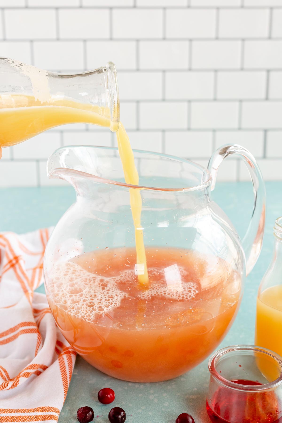 pouring orange juice into a glass pitcher