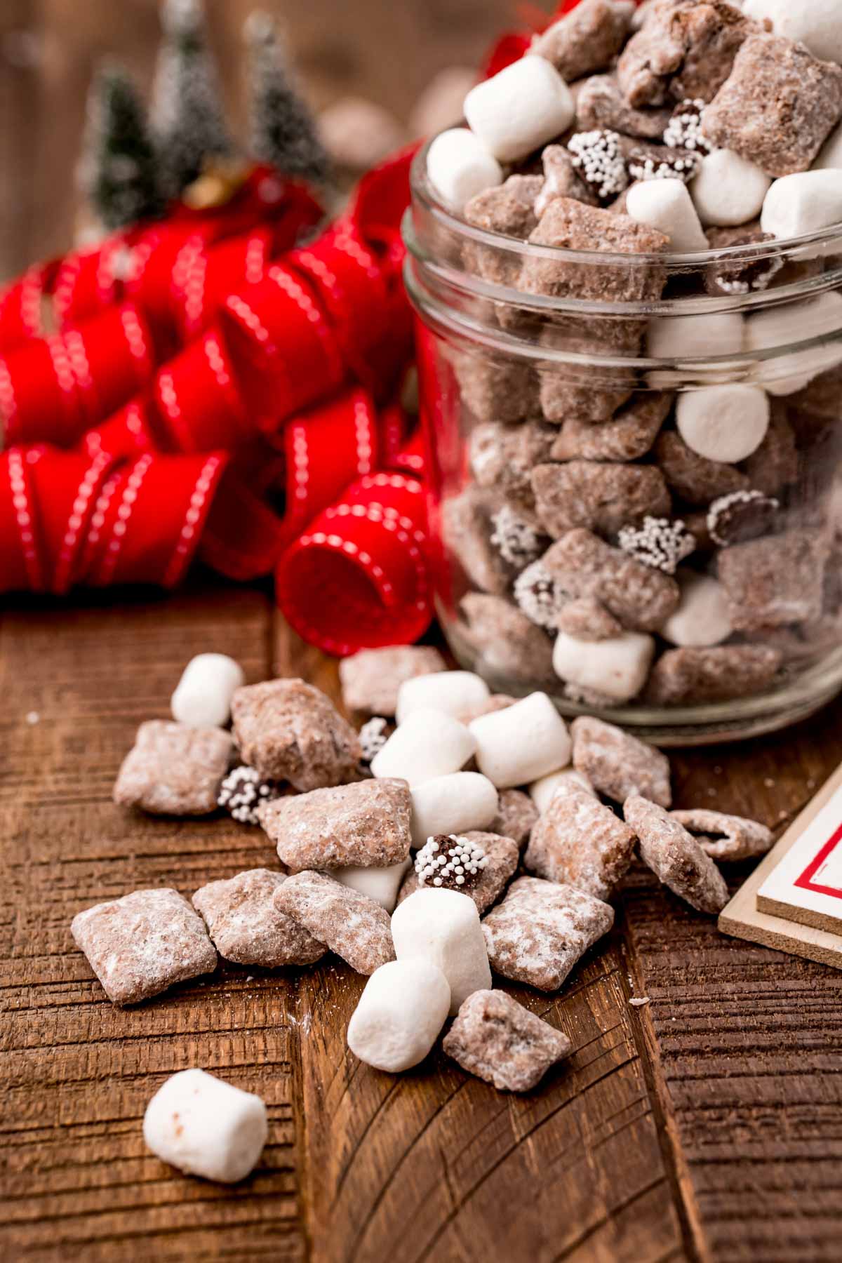 spilled Christmas muddy buddies by a glass jar full