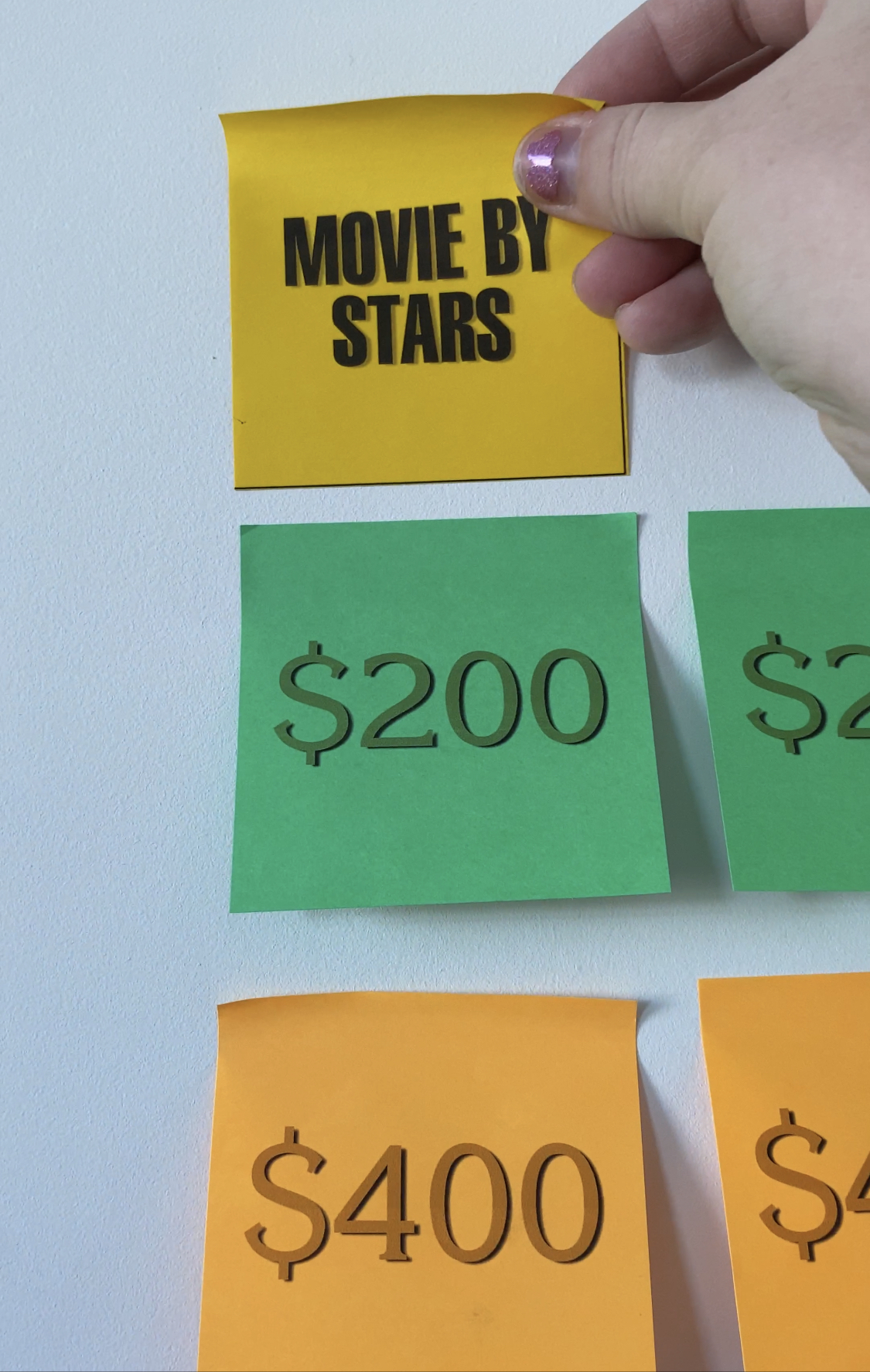 Hanging a Jeopardy category post-it note on a wall