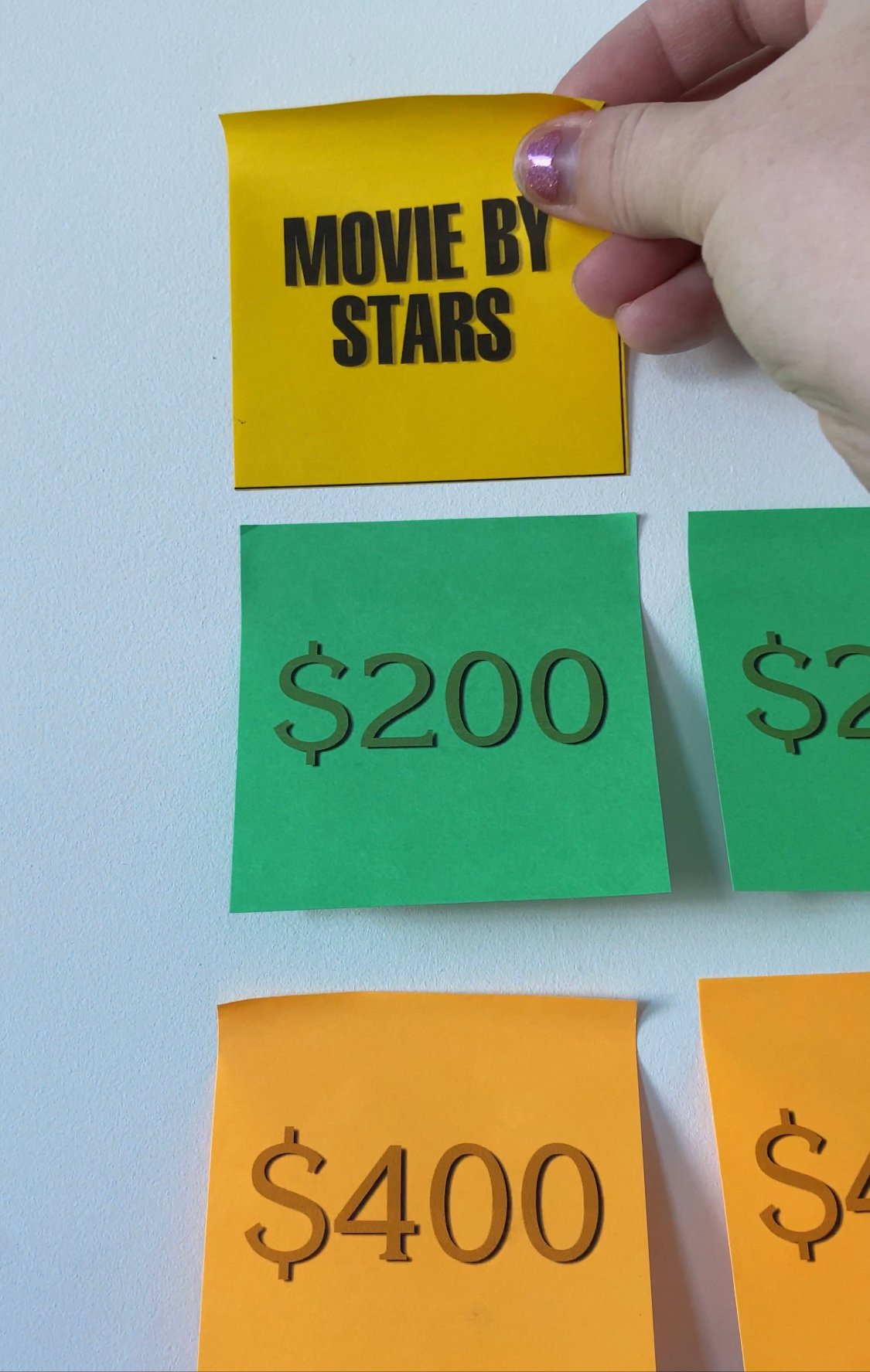 Hanging a Jeopardy category post-it note on a wall