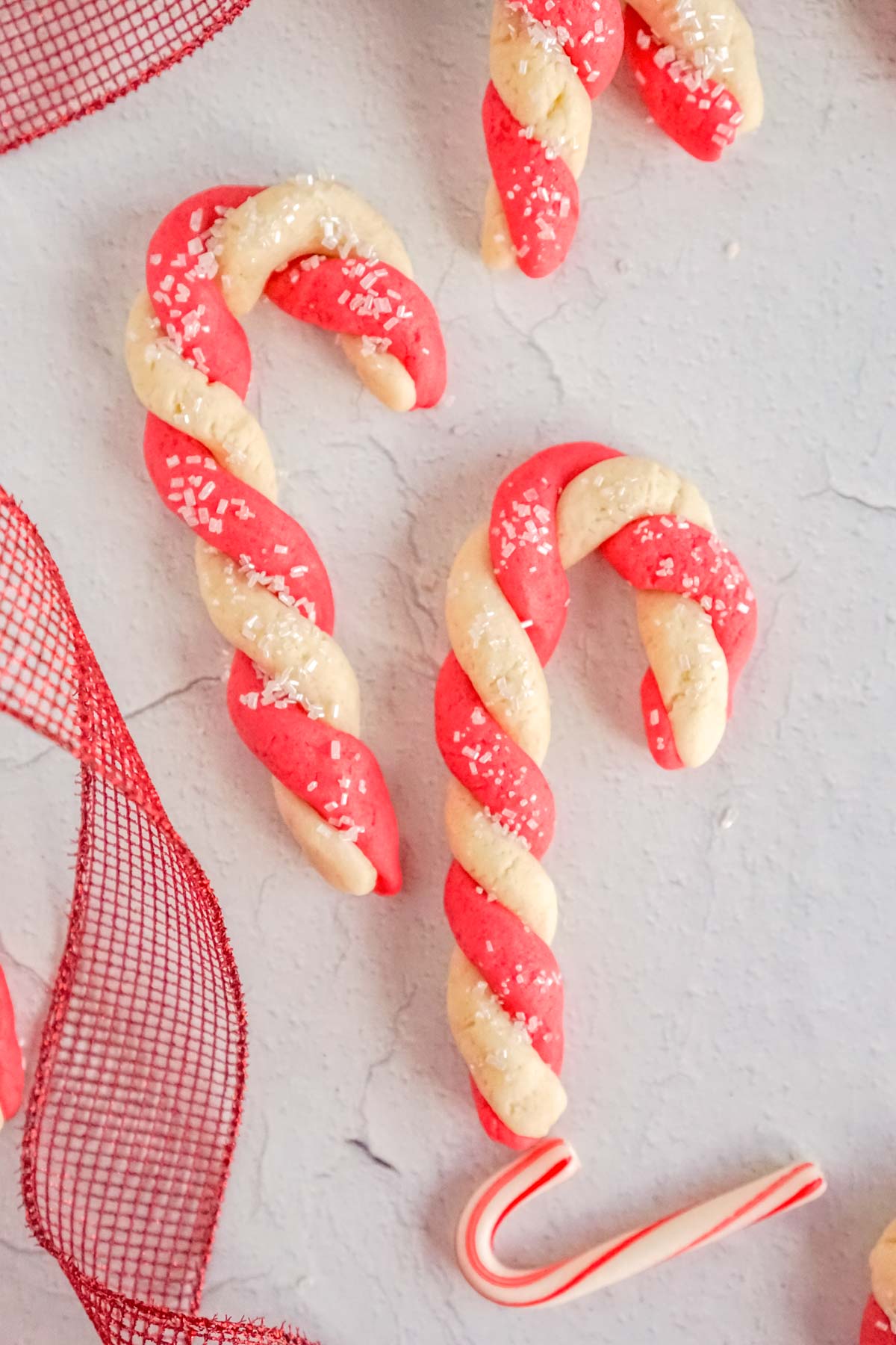 two candy cane sugar cookies with red ribbon