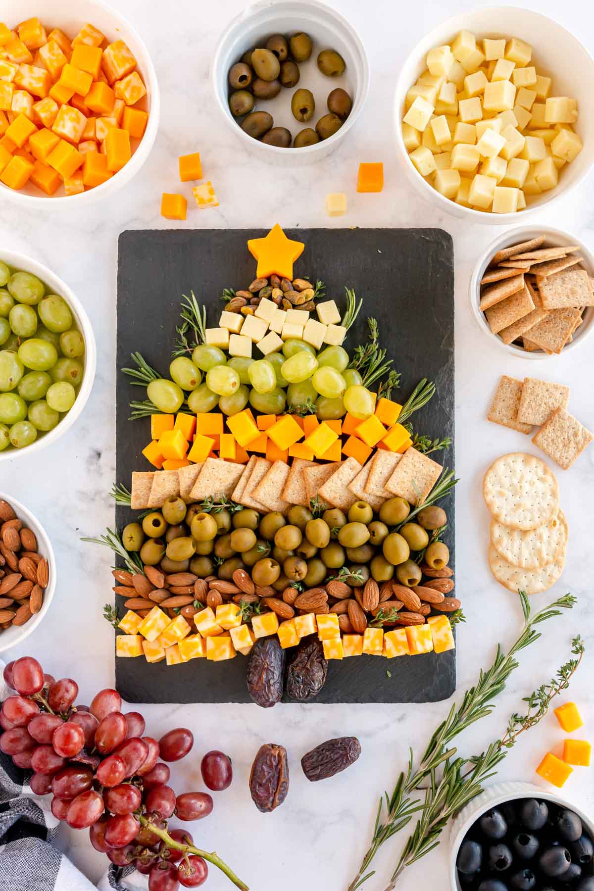 Christmas tree cheese board with ingredients all around