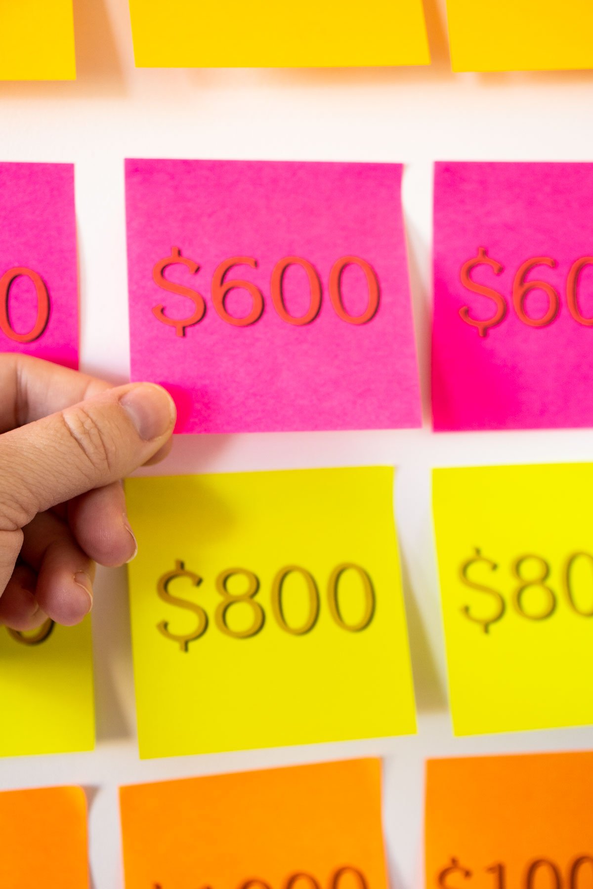 Hand removing a post-it note from a Christmas Jeopardy board