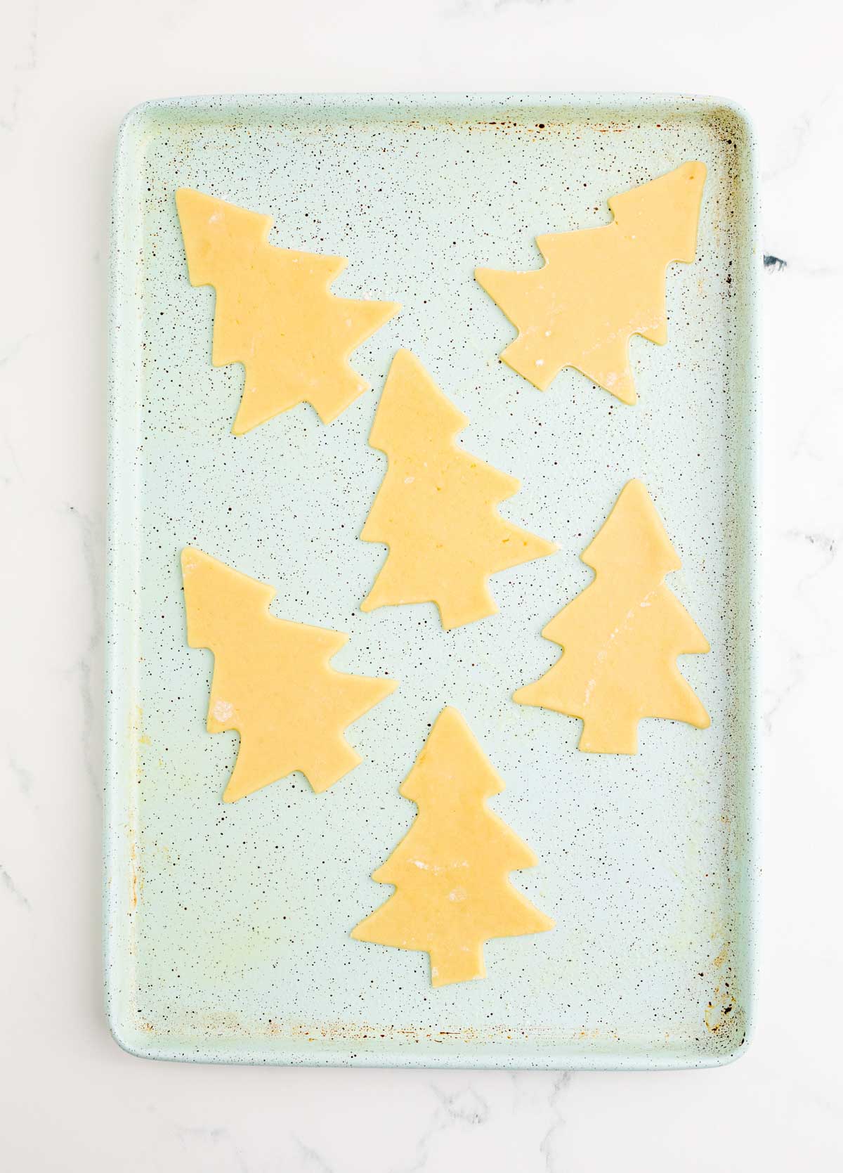 unbaked Christmas tree cookies on a baking sheet