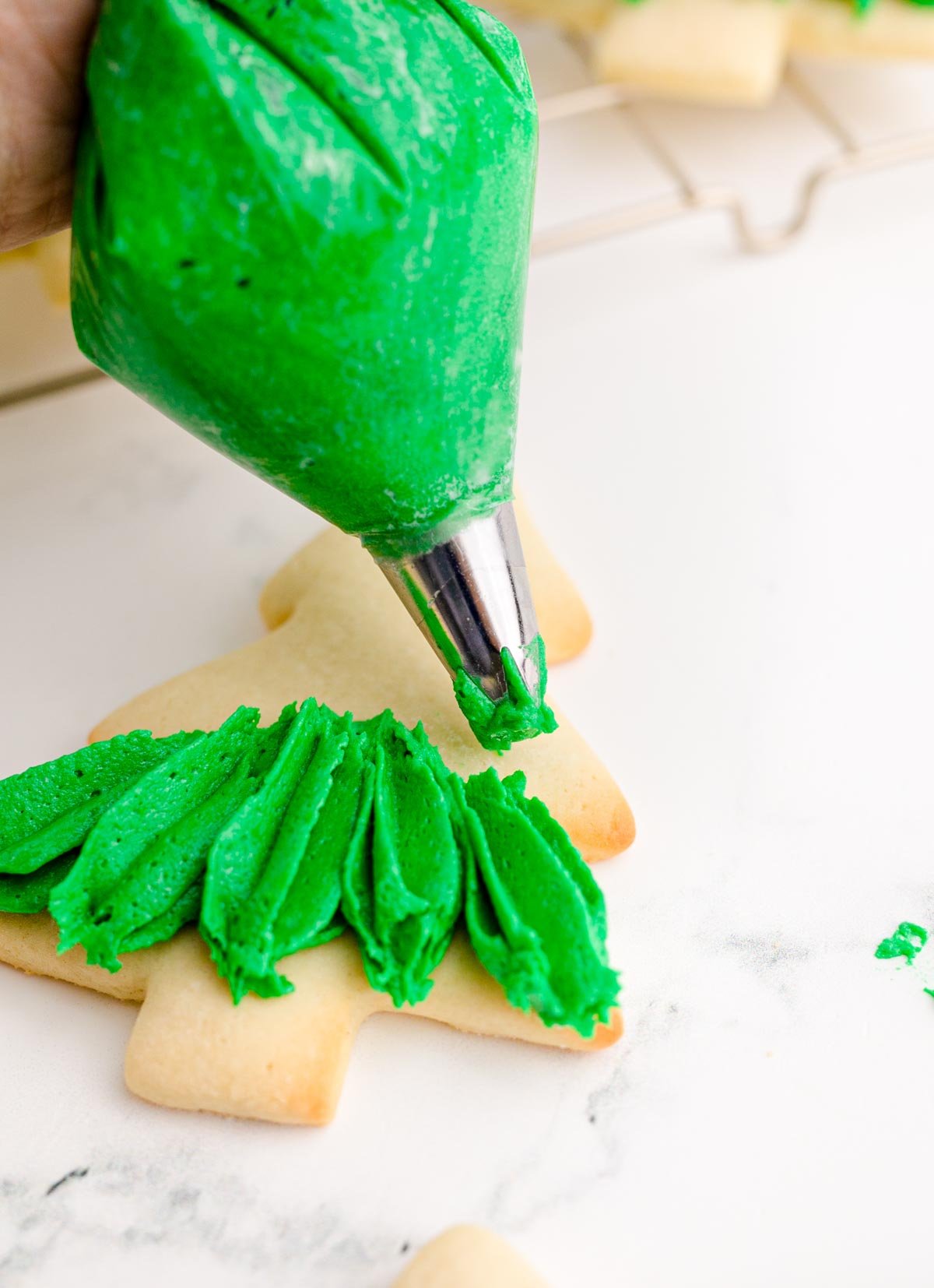 piping frosting onto Christmas tree cookies