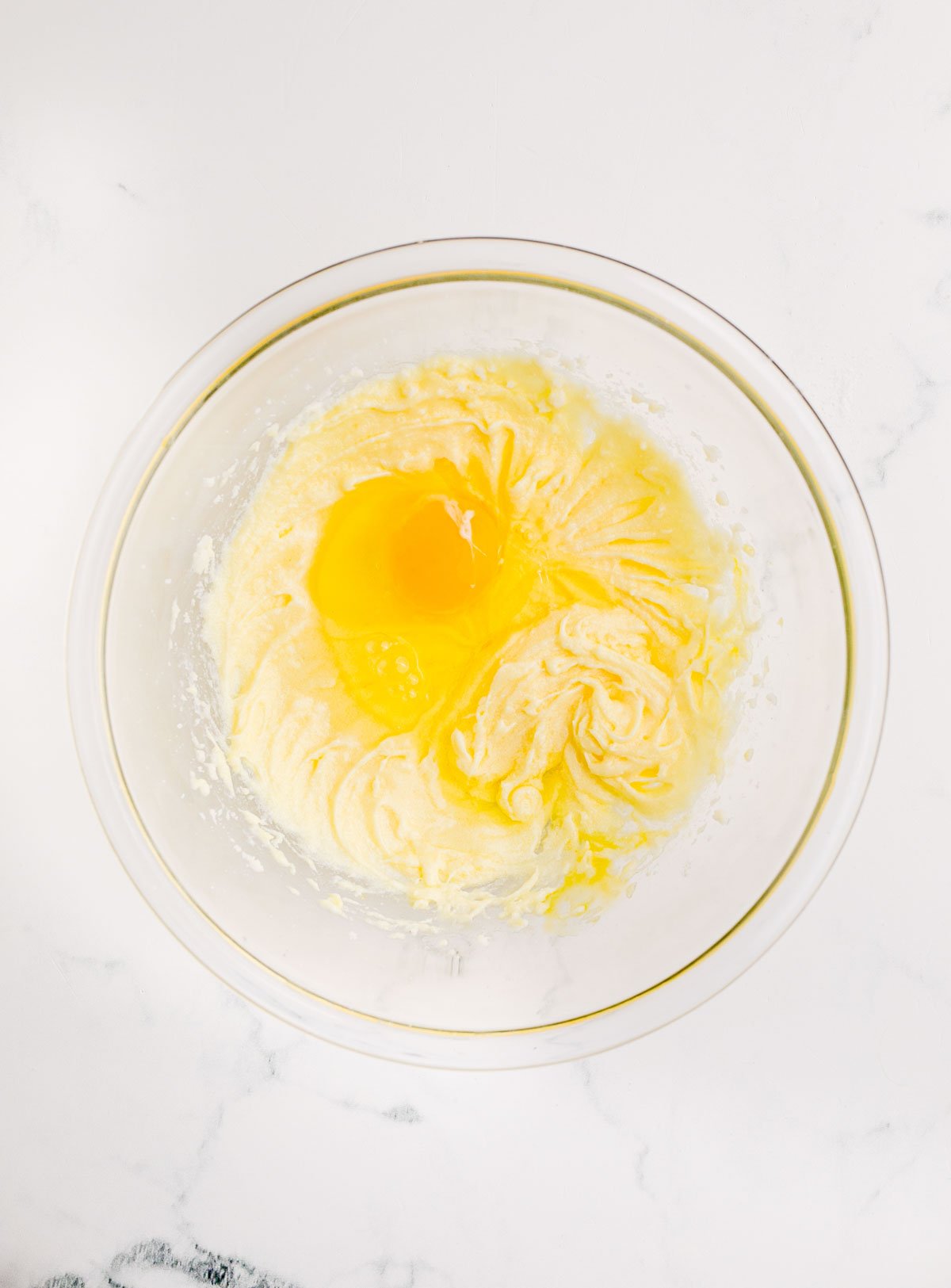 eggs being creamed into a bowl of sugar