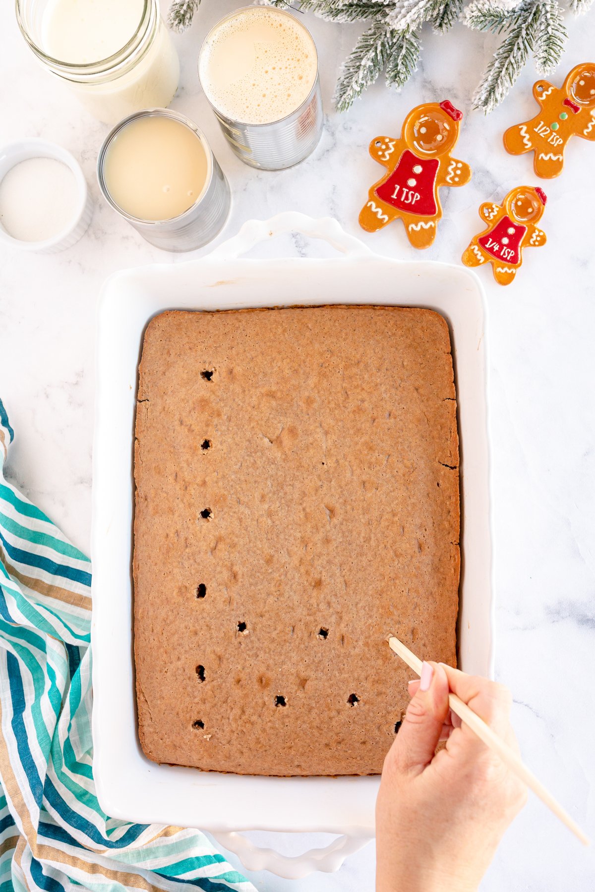 hand putting holes in a baked gingerbread cake