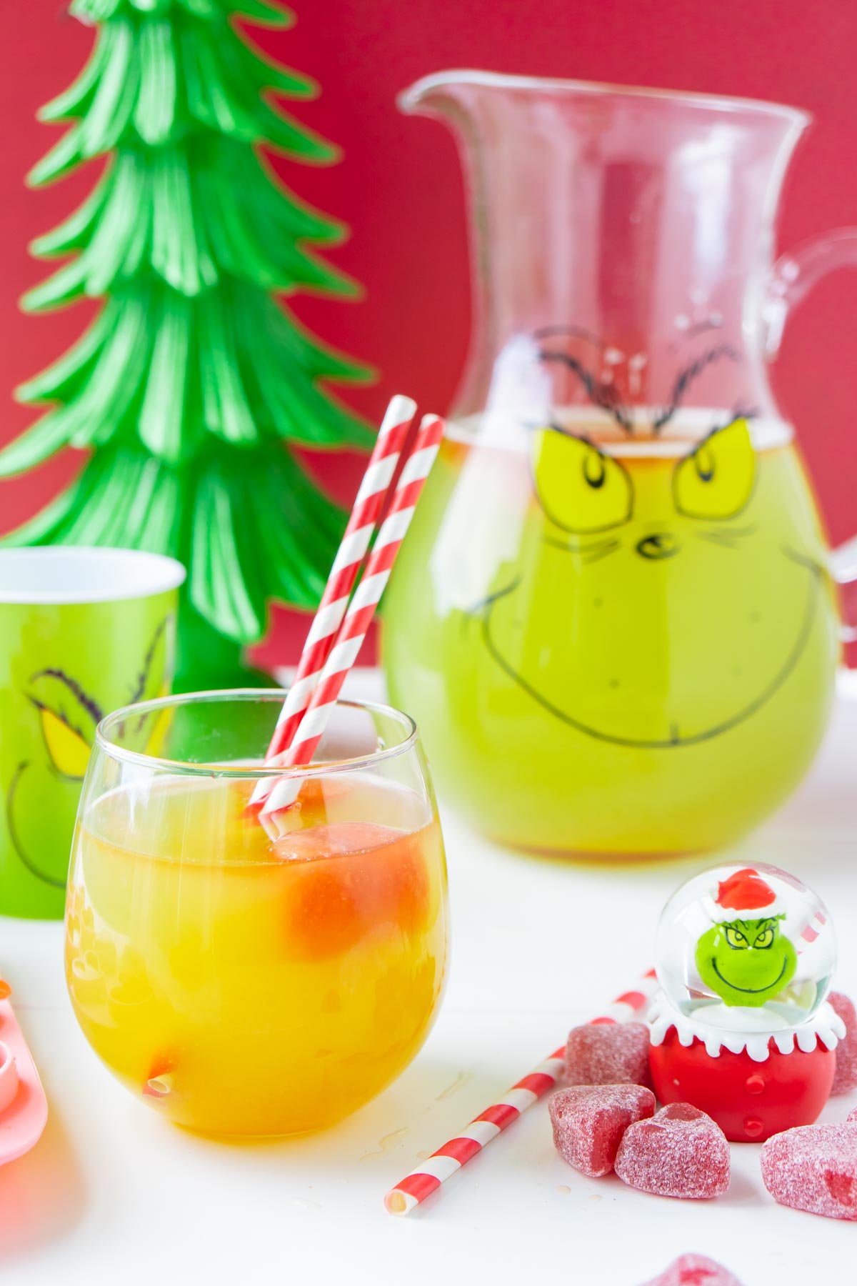 Grinch punch in a glass pitcher with a red straw