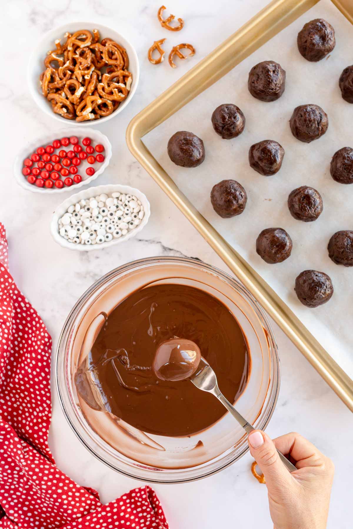 brownie ball dipped in chocolate above a glass bowl of chooclate