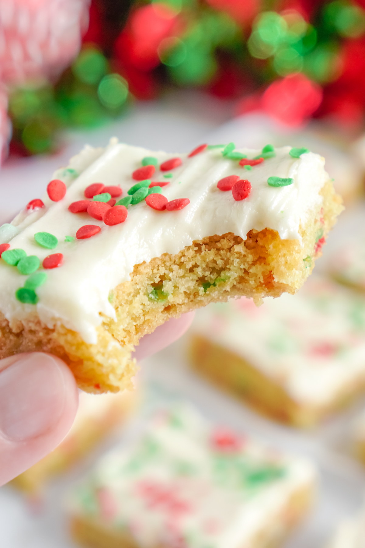 Hand holding a Christmas sugar cookie bar with a bite out of it