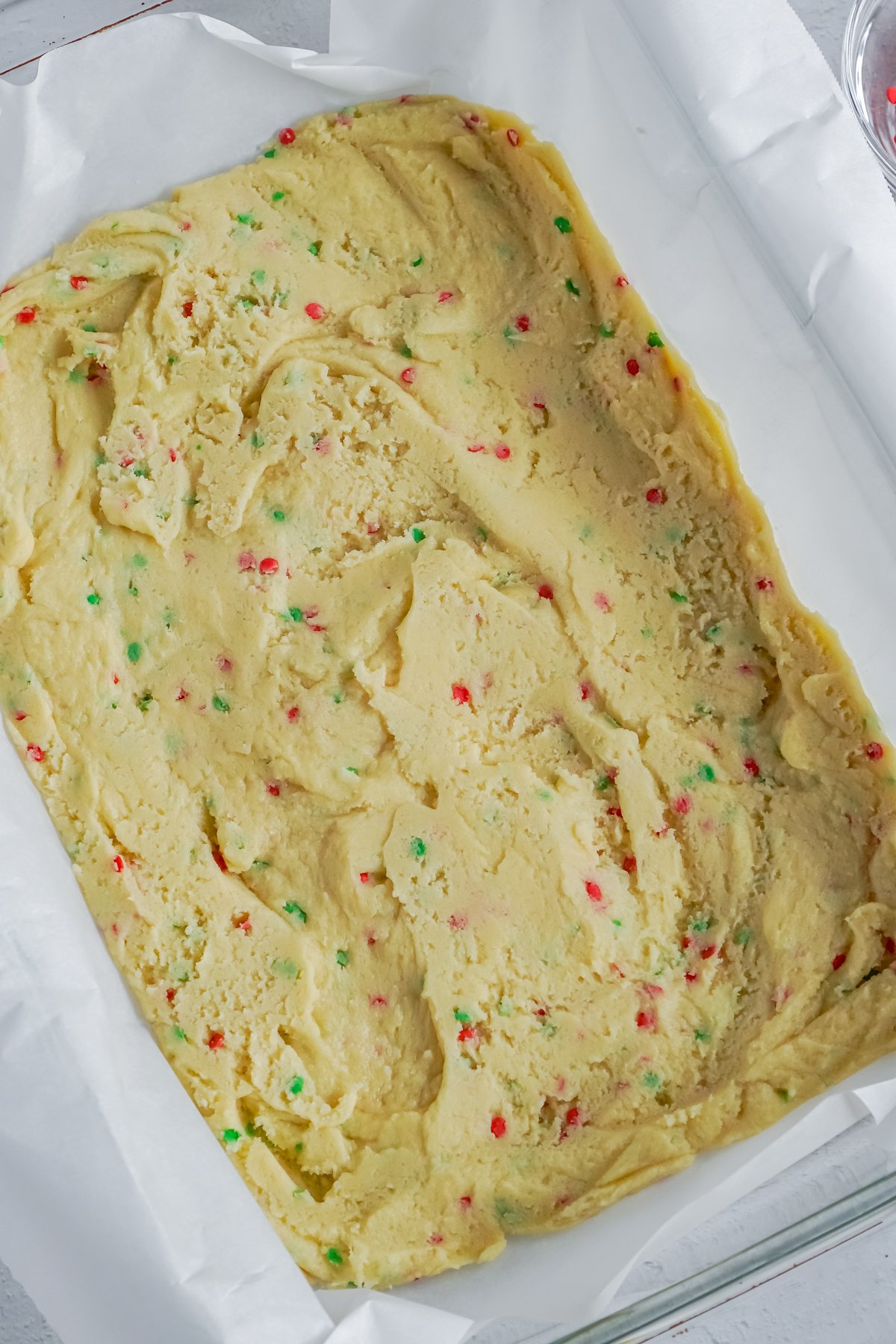 dough for sugar cookie bars in a white baking dish