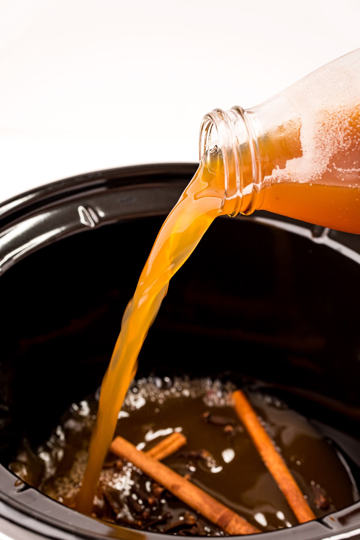 pouring apple cider into a crock pot