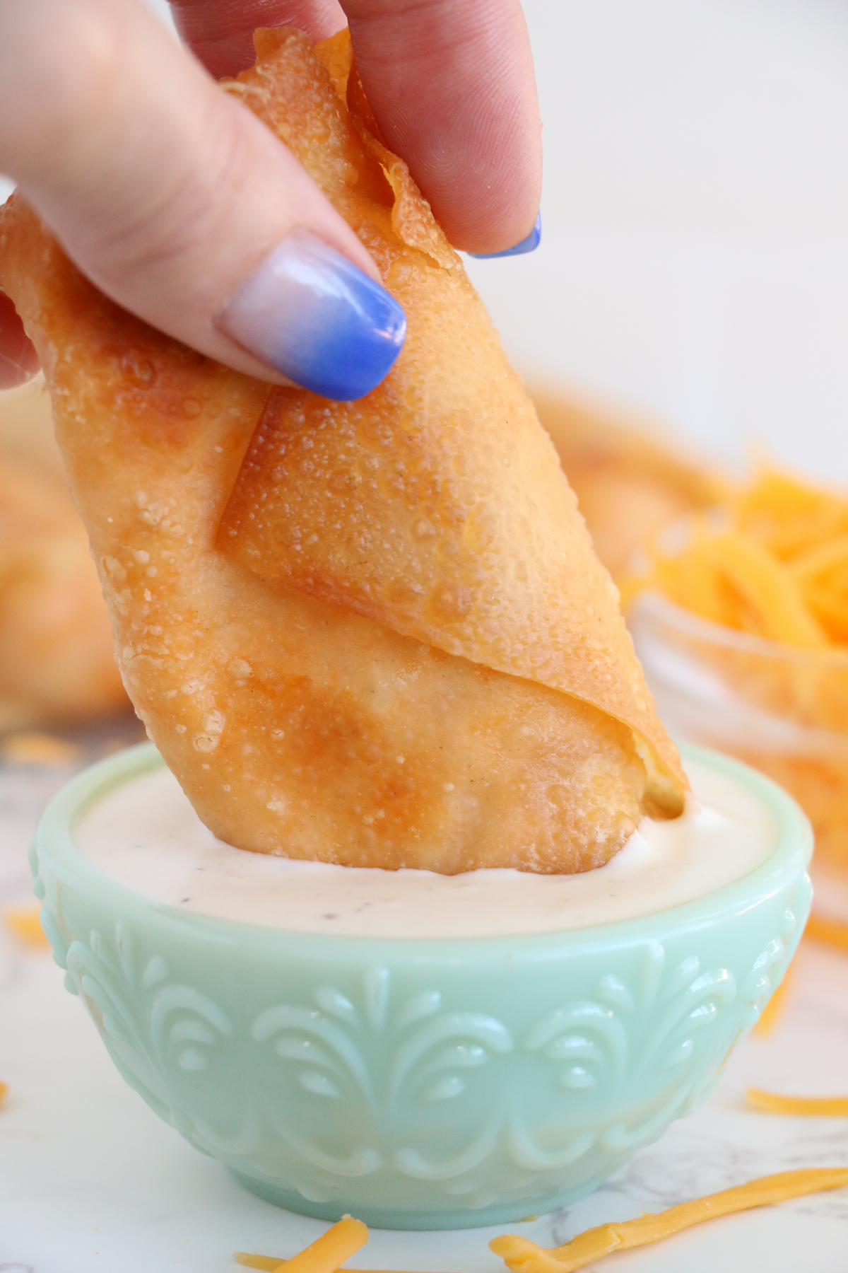 hand dipping a buffalo chicken egg roll into ranch dressing