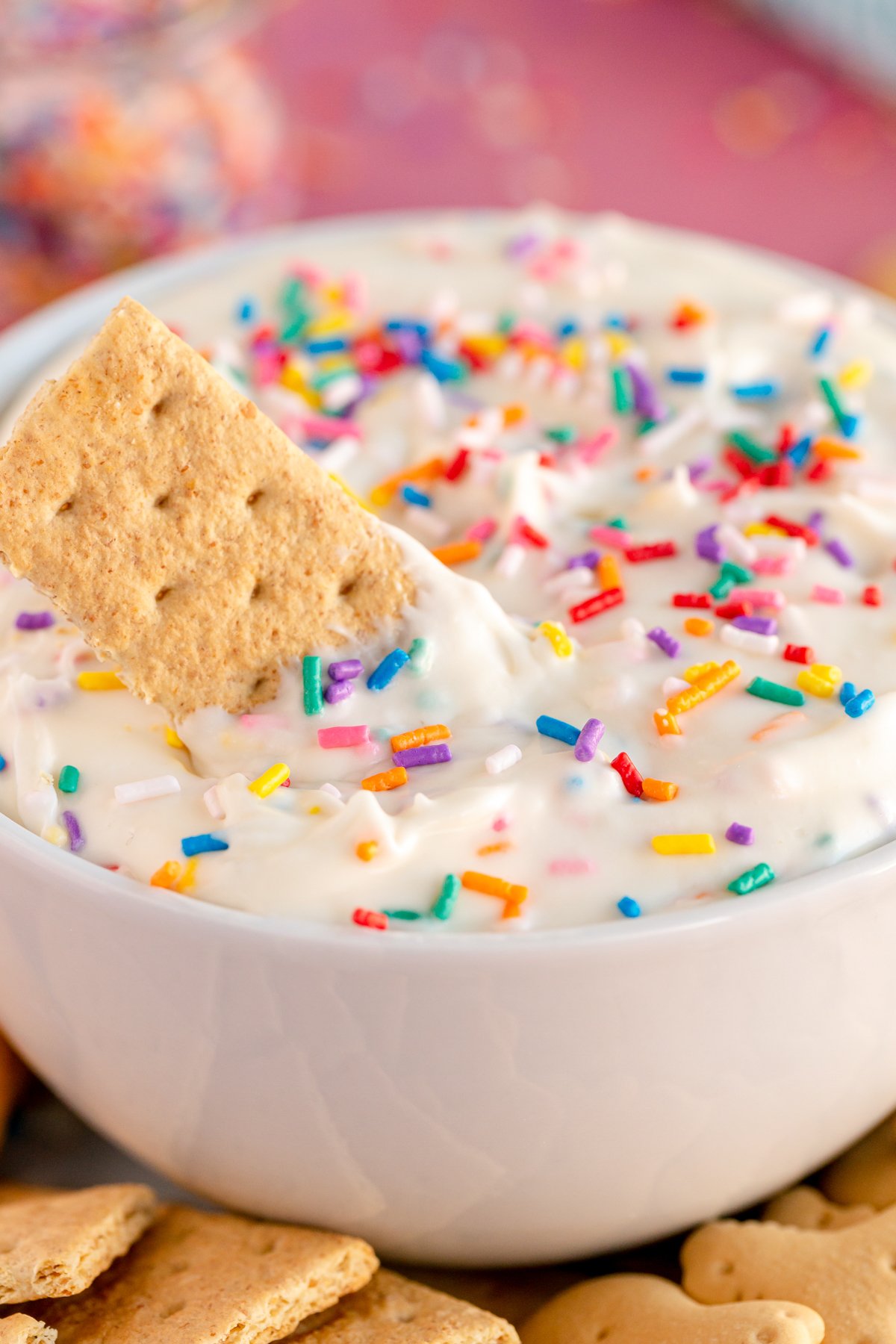 white bowl with funfetti dip and a graham cracker on top