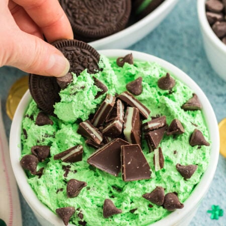 hand dipping an Oreo in a grasshopper dessert dip