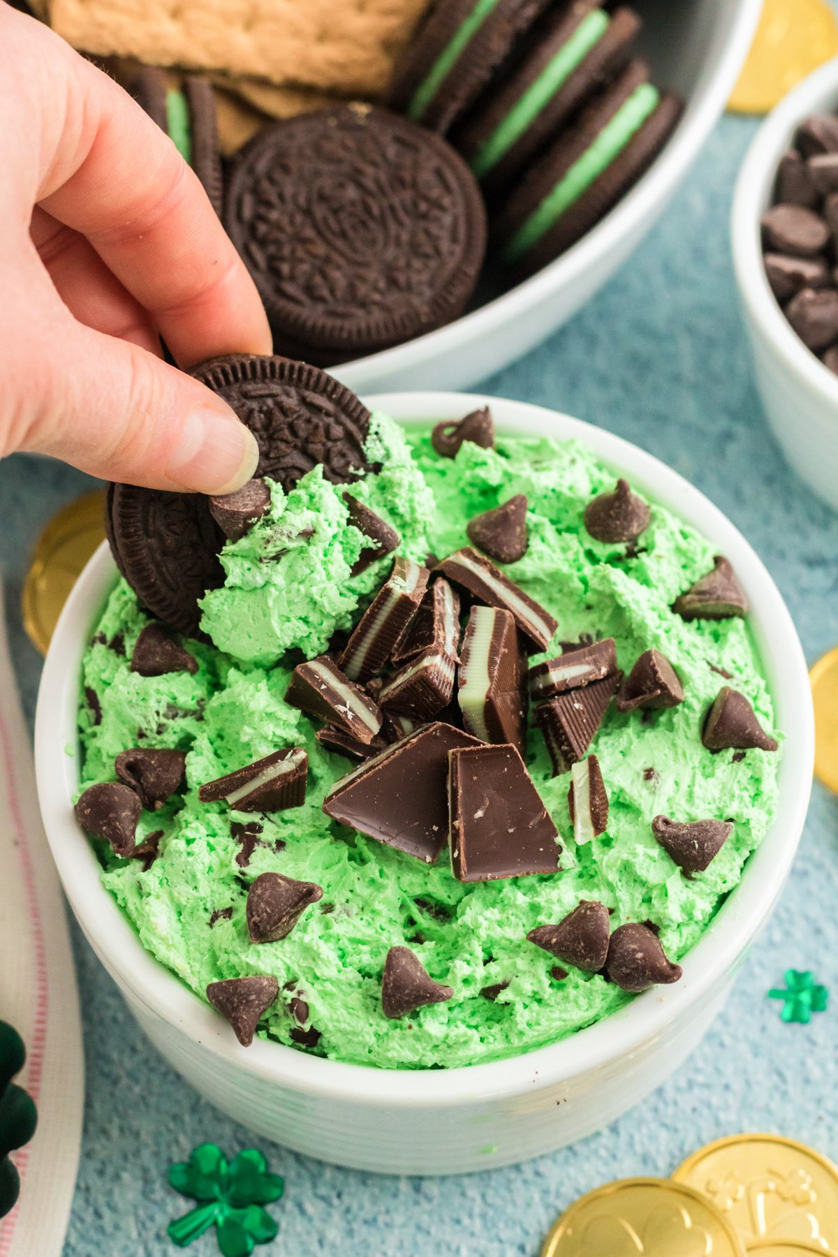 hand dipping an Oreo in a grasshopper dessert dip