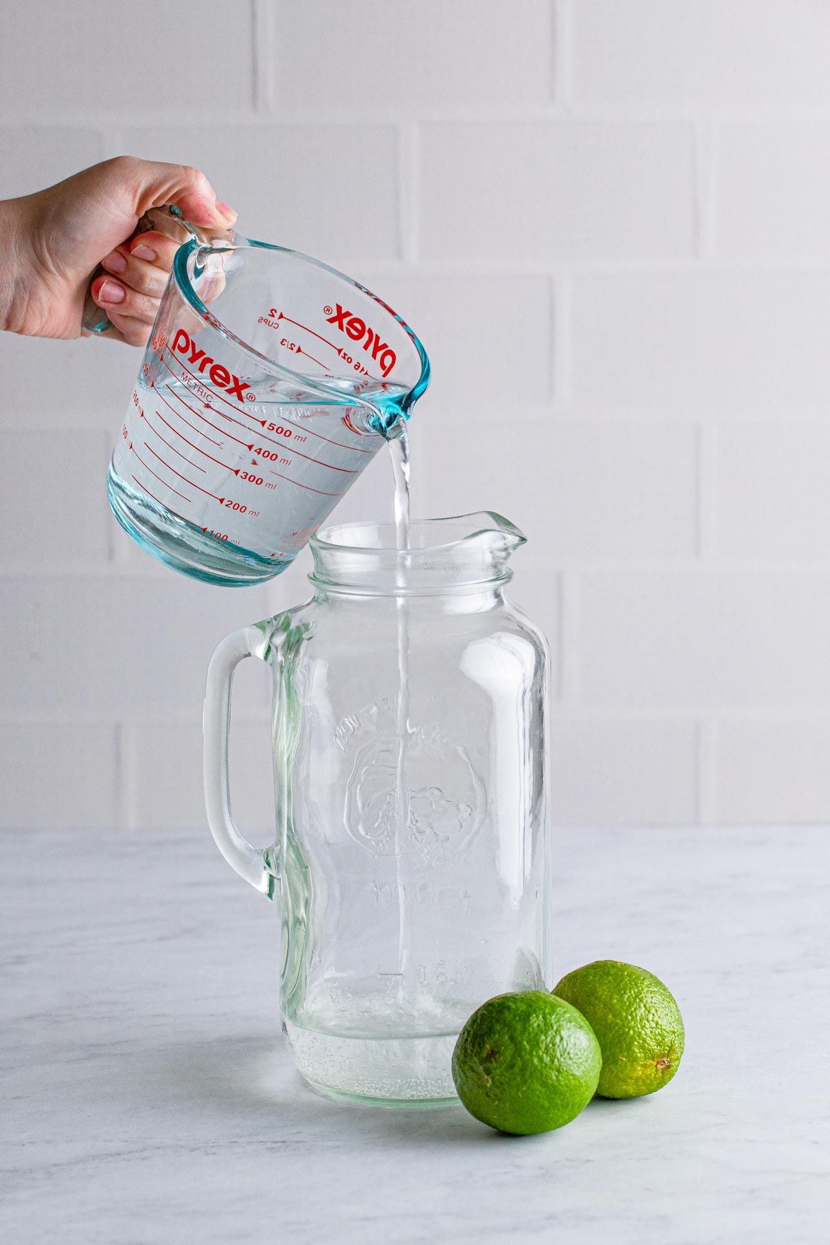 pouring Sprite into a glass pitcher