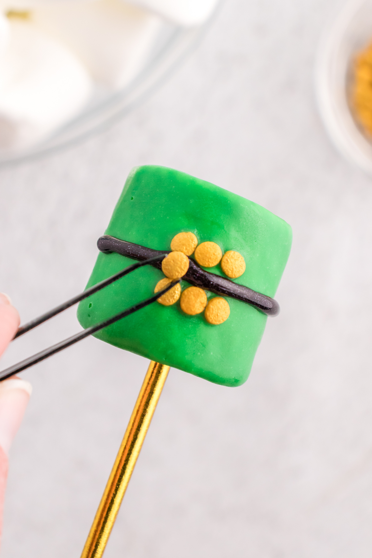 adding confetti sprinkles to a green marshmallow