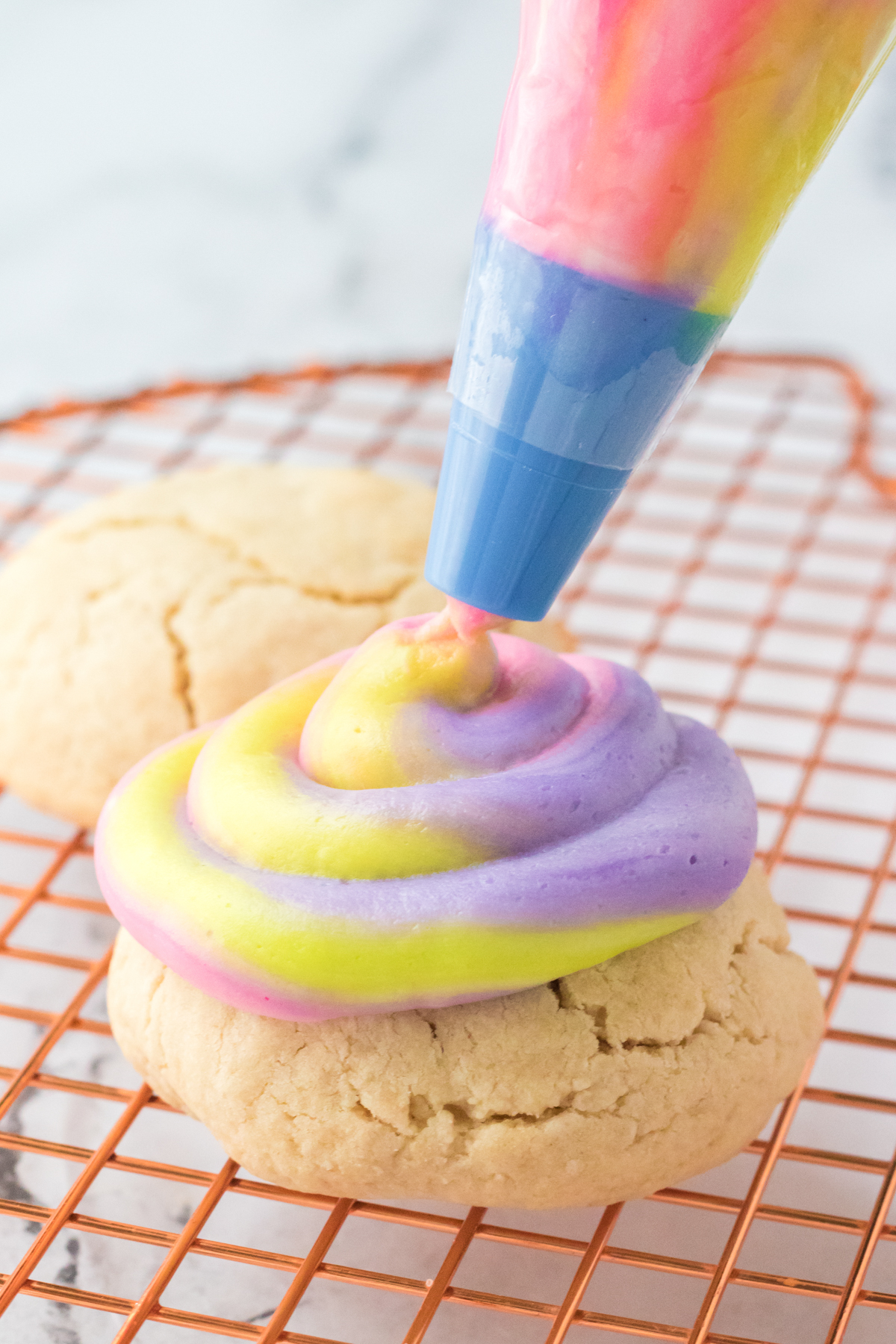 piping swirled frosting onto lemon cookies