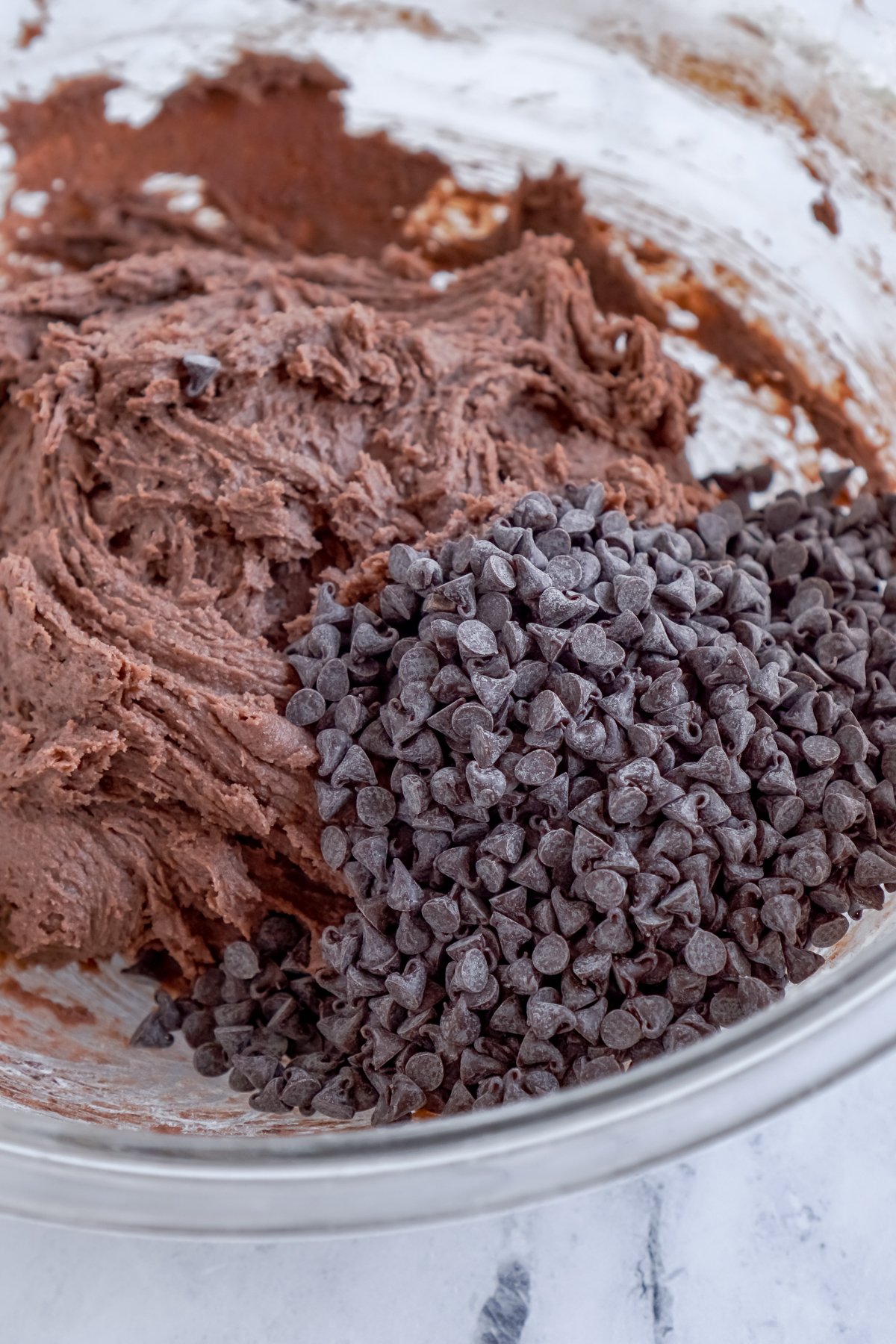 adding mini chocolate chips to a chocolate cookie batter