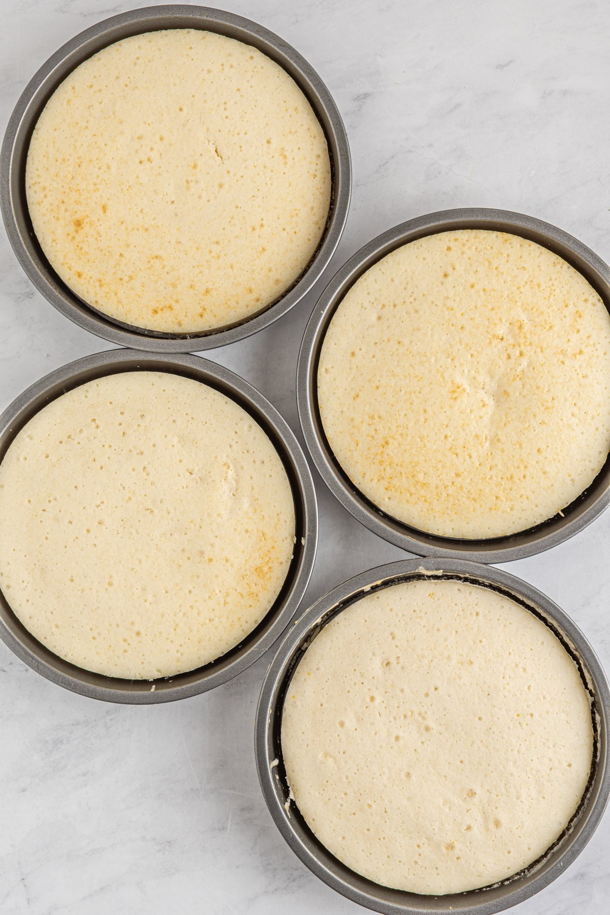 four round cake pans with white cake