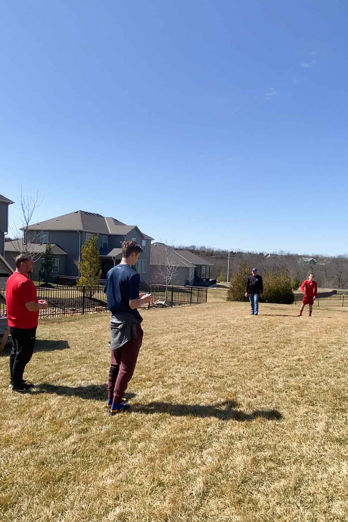 teens and adult men standing in a yard