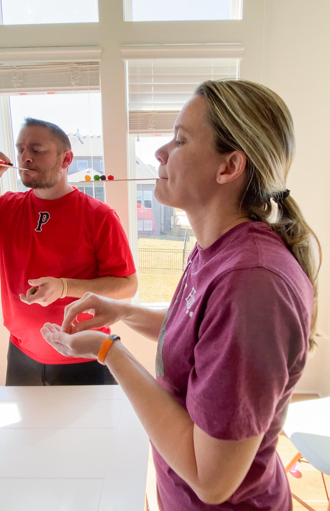 woman balancing jelly beans on a popsicle stick in her mouth