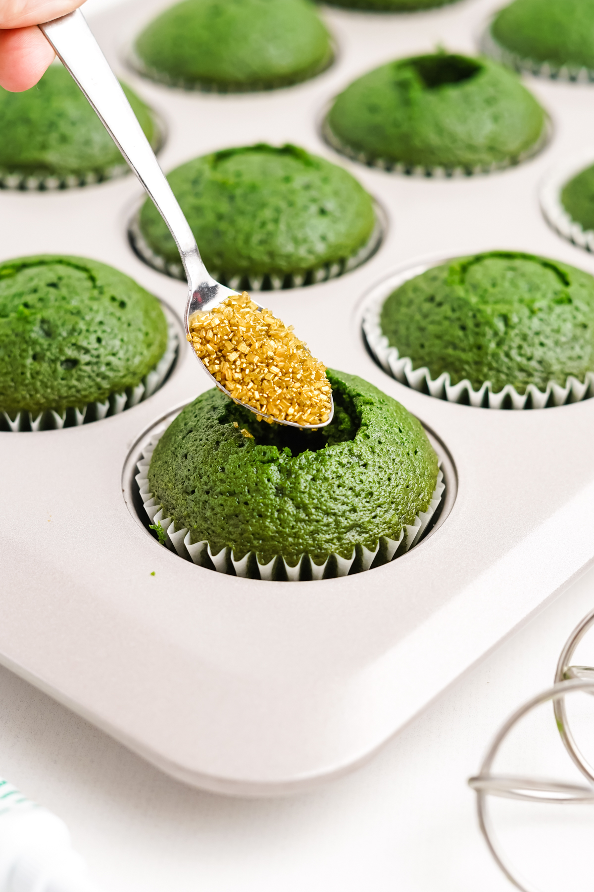 filling green velvet cupcakes with gold sprinkles