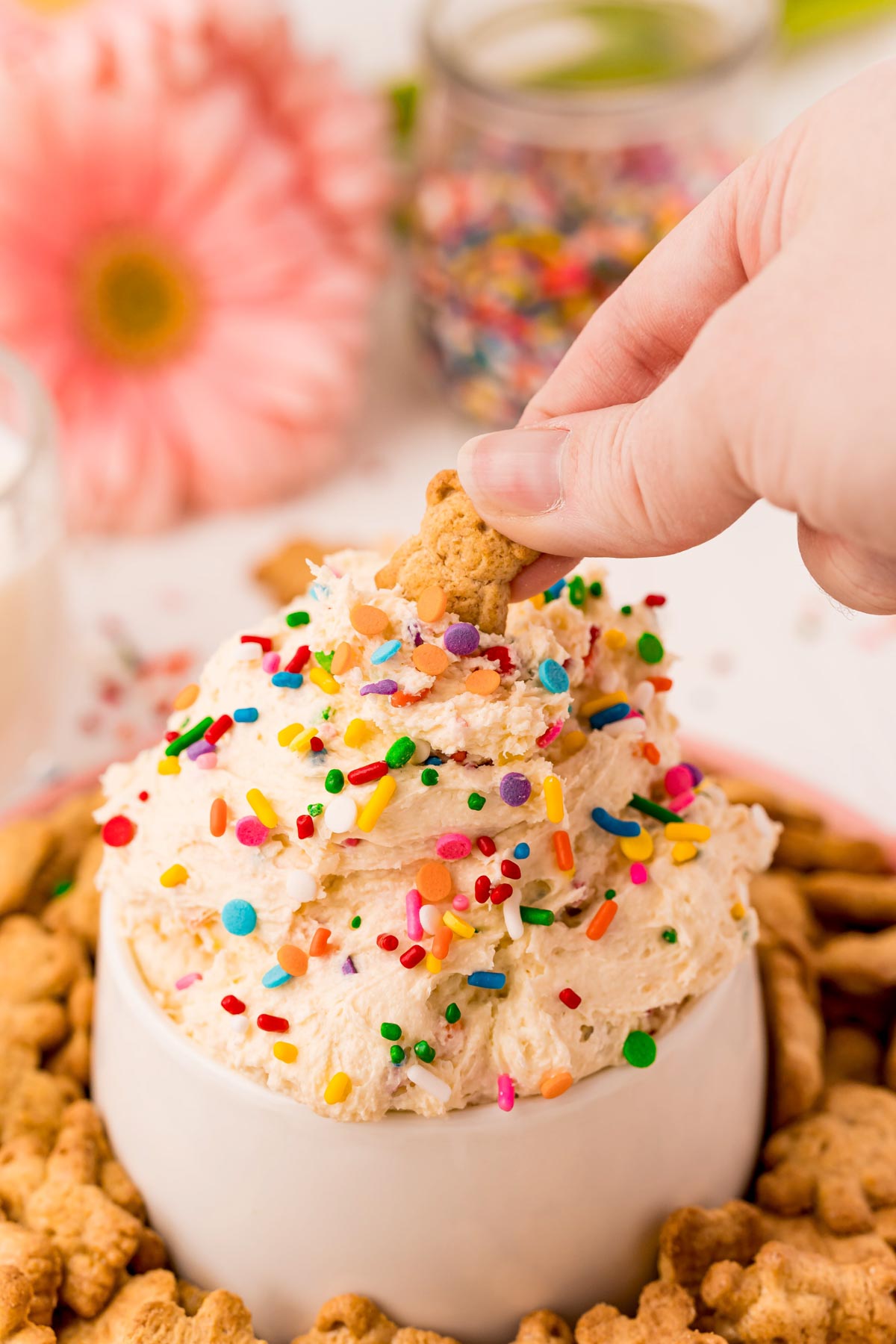 hand dipping a Teddy Graham into dunkaroo dip