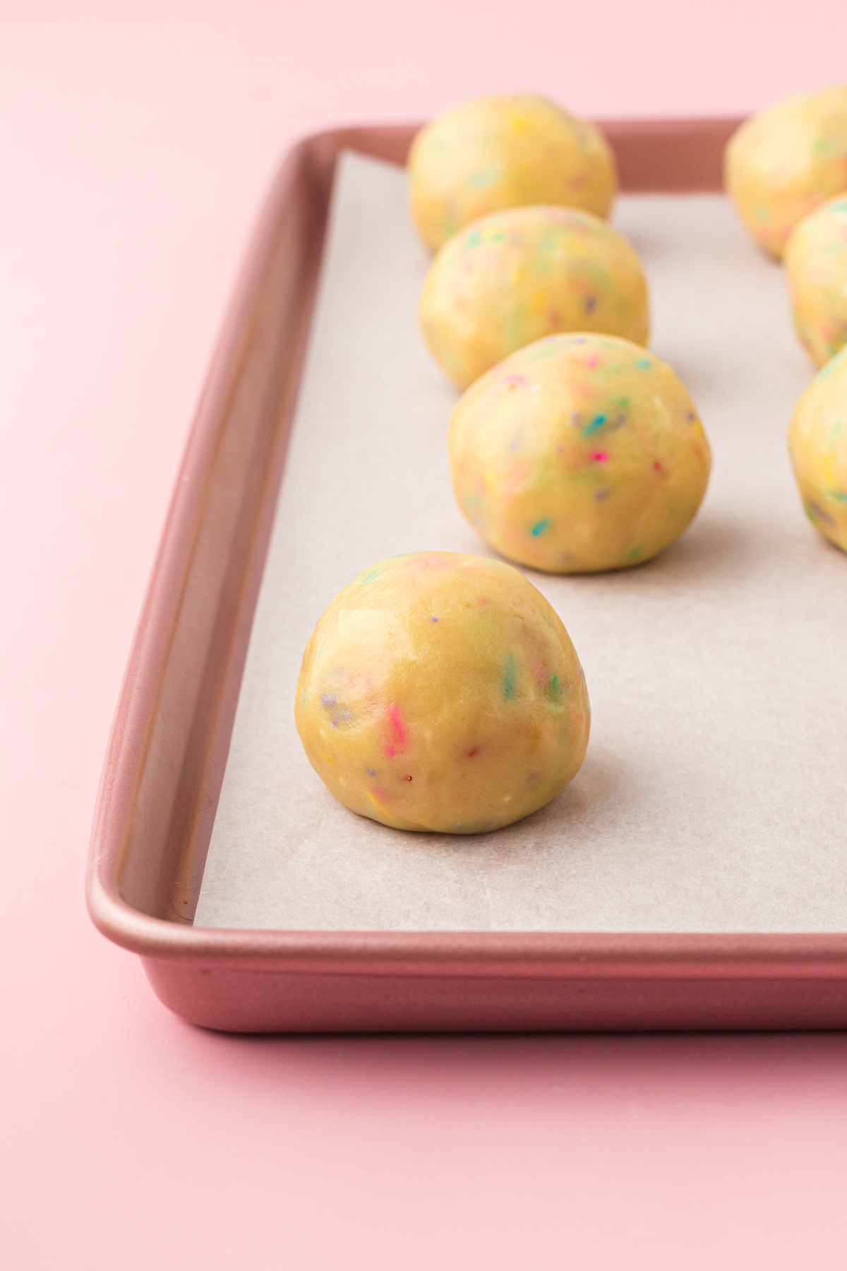 unbaked Lucky Charms cookie dough balls on a baking sheet