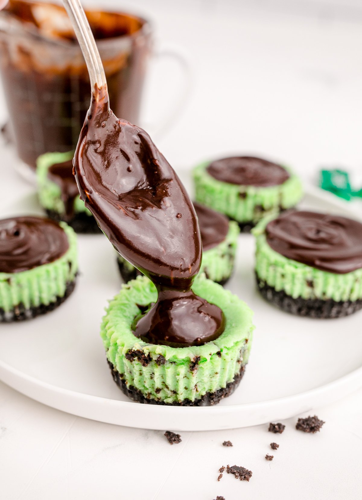 adding chocolate ganache on top of a mint chocolate cheesecake