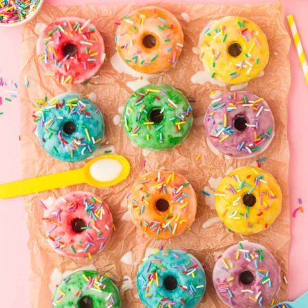frosted rainbow donuts on a piece of parchment